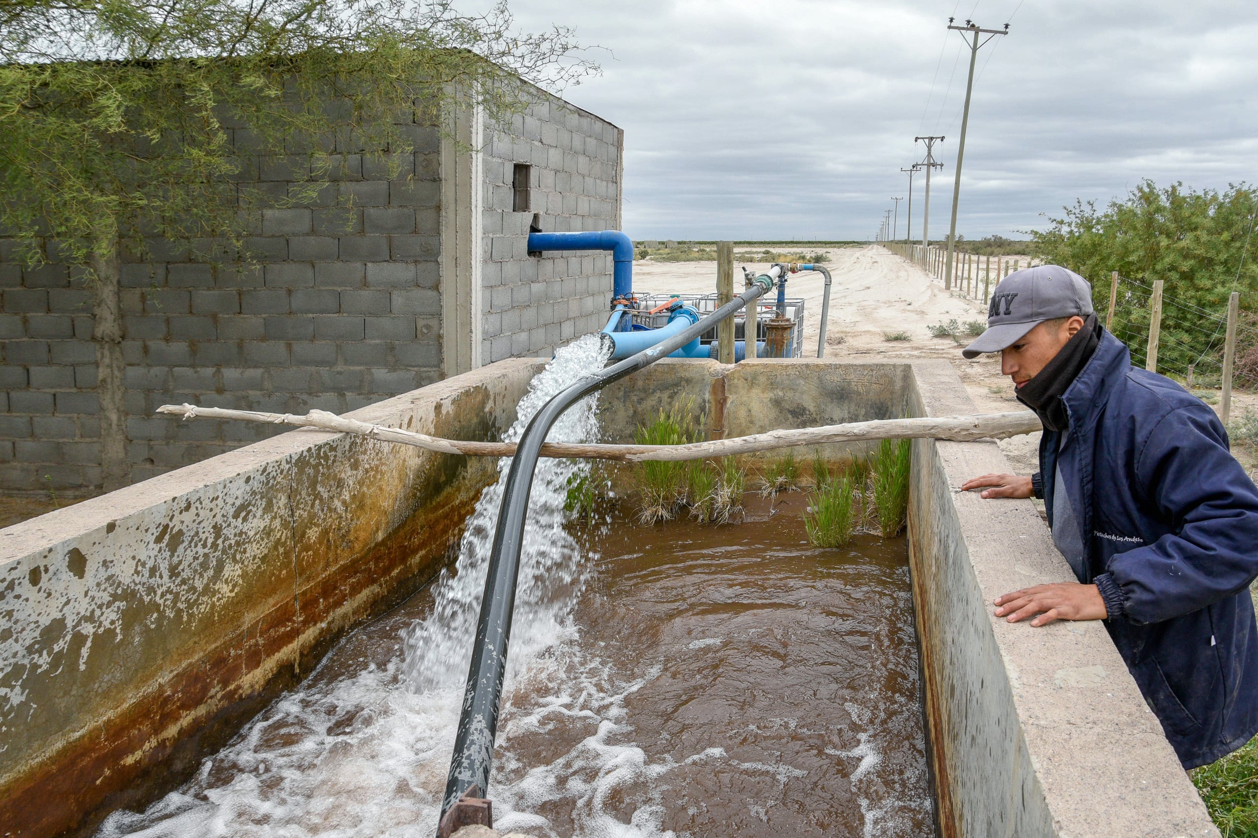 Un hombre de pie junto a una bomba de agua