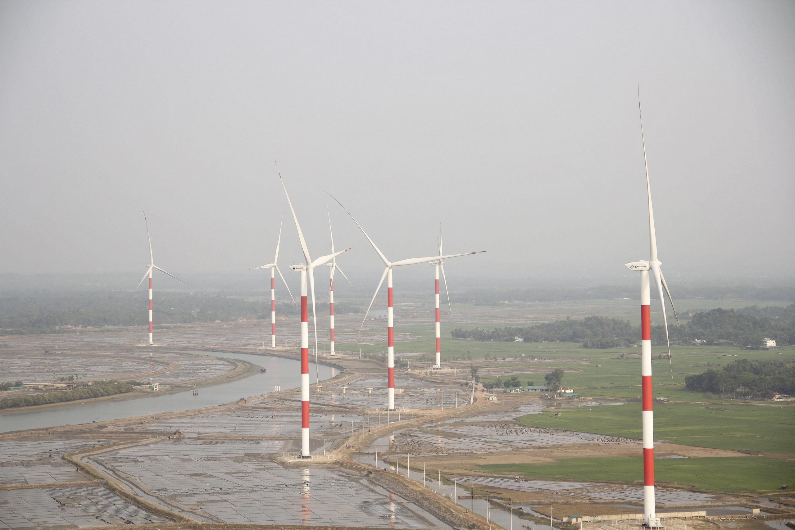 A landscape featuring several wind turbines with red and white stripes