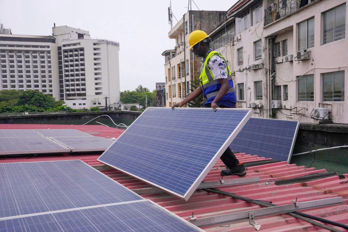man holding solar panel on roof