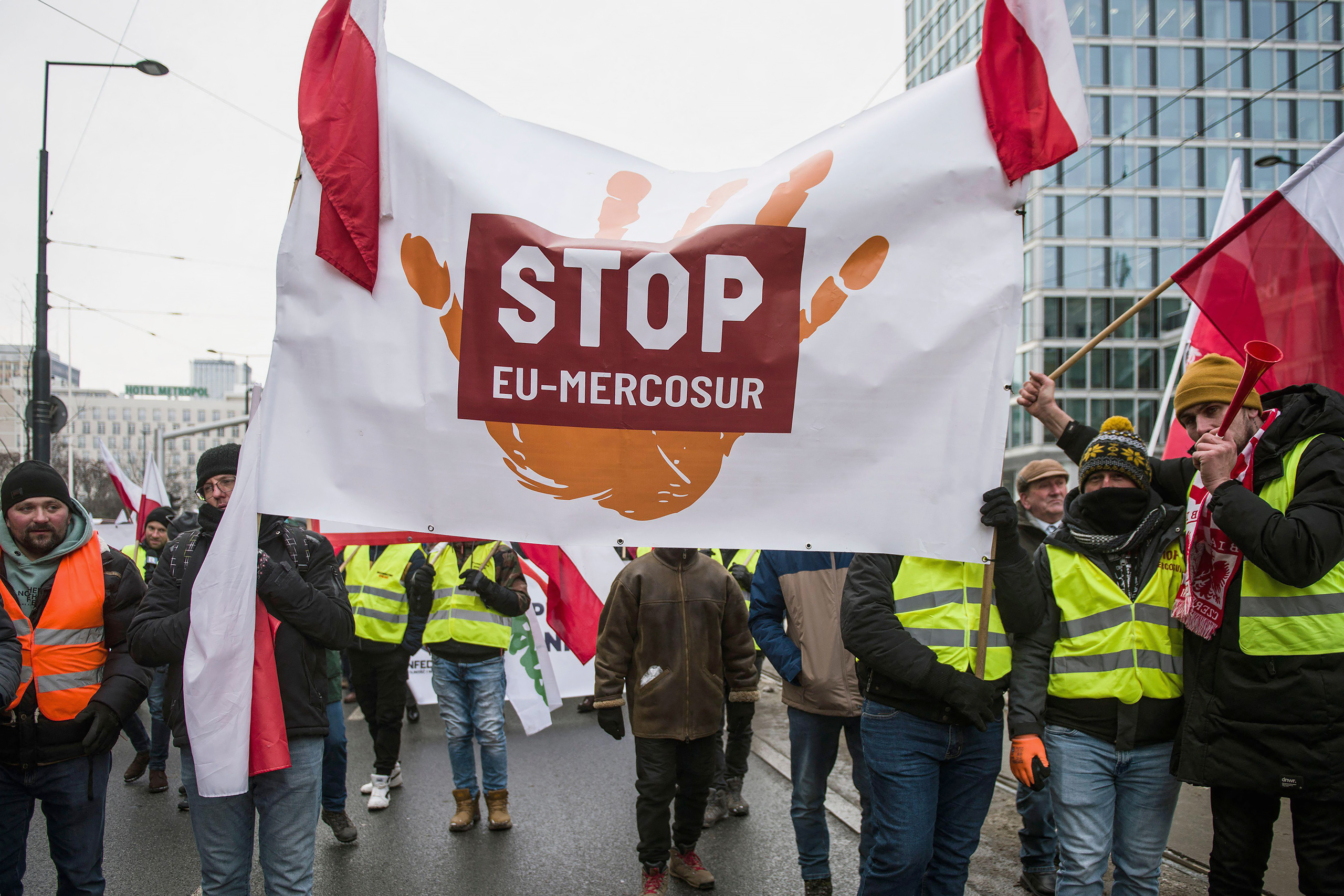 Protesters hold a large banner reading "STOP EU-Mercosur" on the street