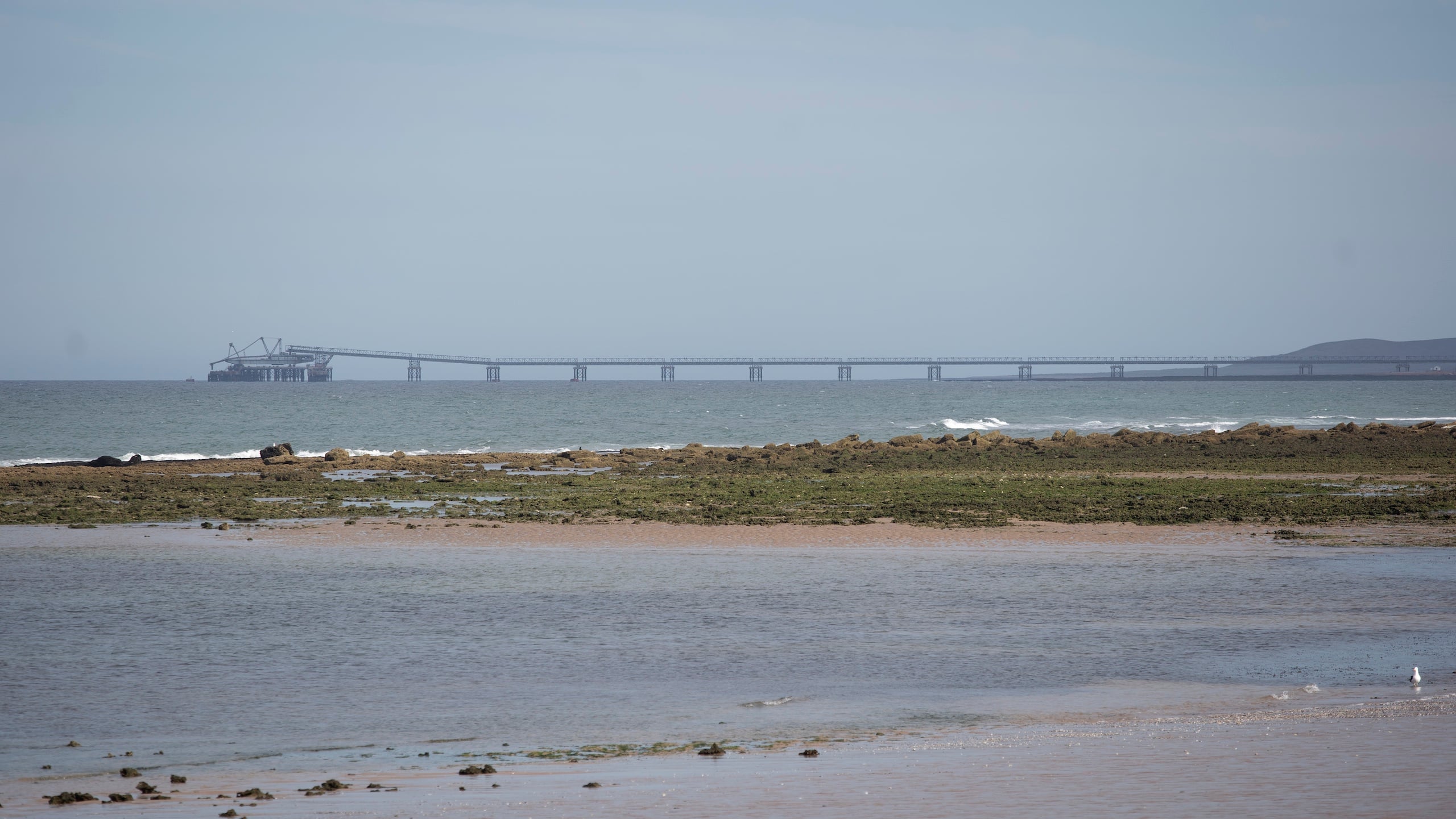 A distant view of a long pier extending over the sea