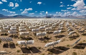 Vast solar energy field with rows of photovoltaic panels under a blue sky