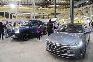 Two BYD vehicles showcased in a car event, with people interacting and viewing the cars