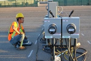 kneeling man surveys electric equipment