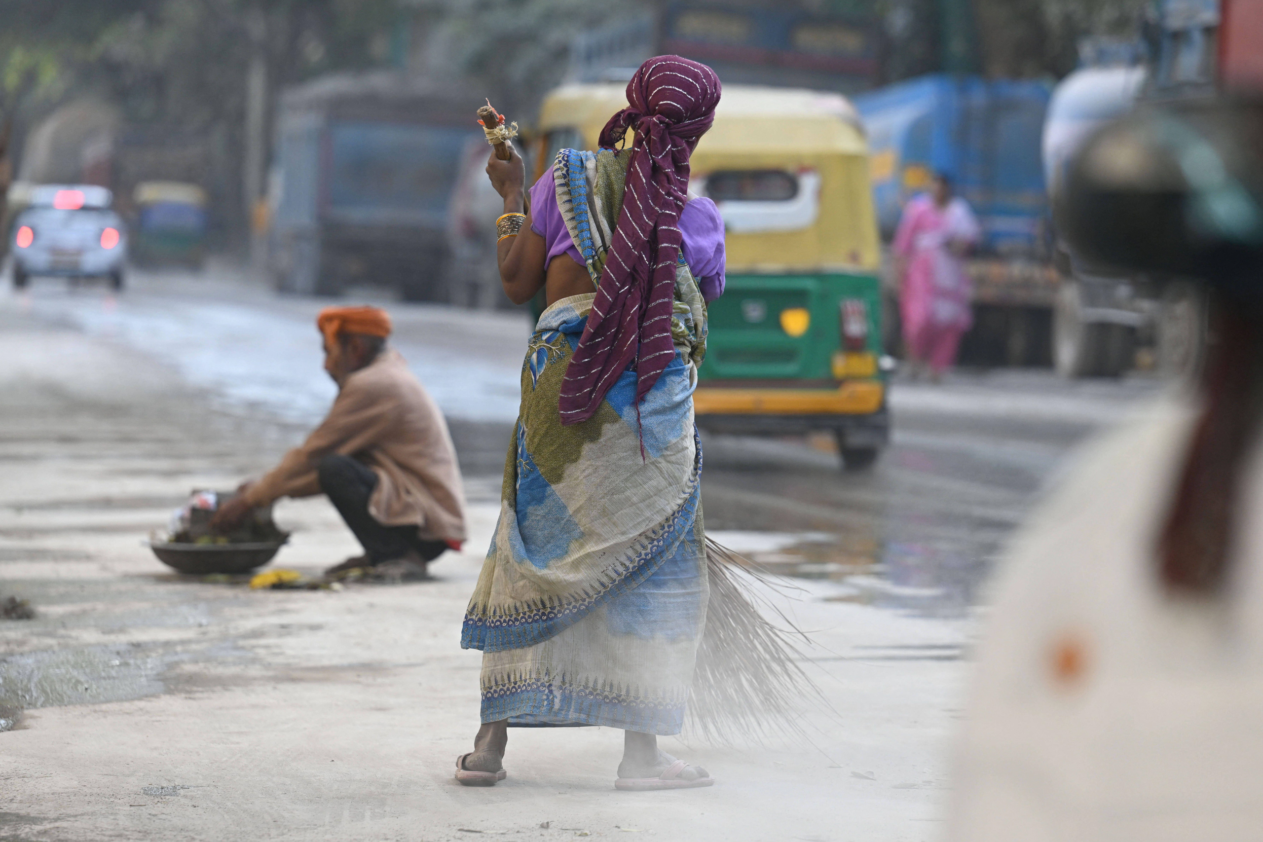 woman sweeping dusty street
