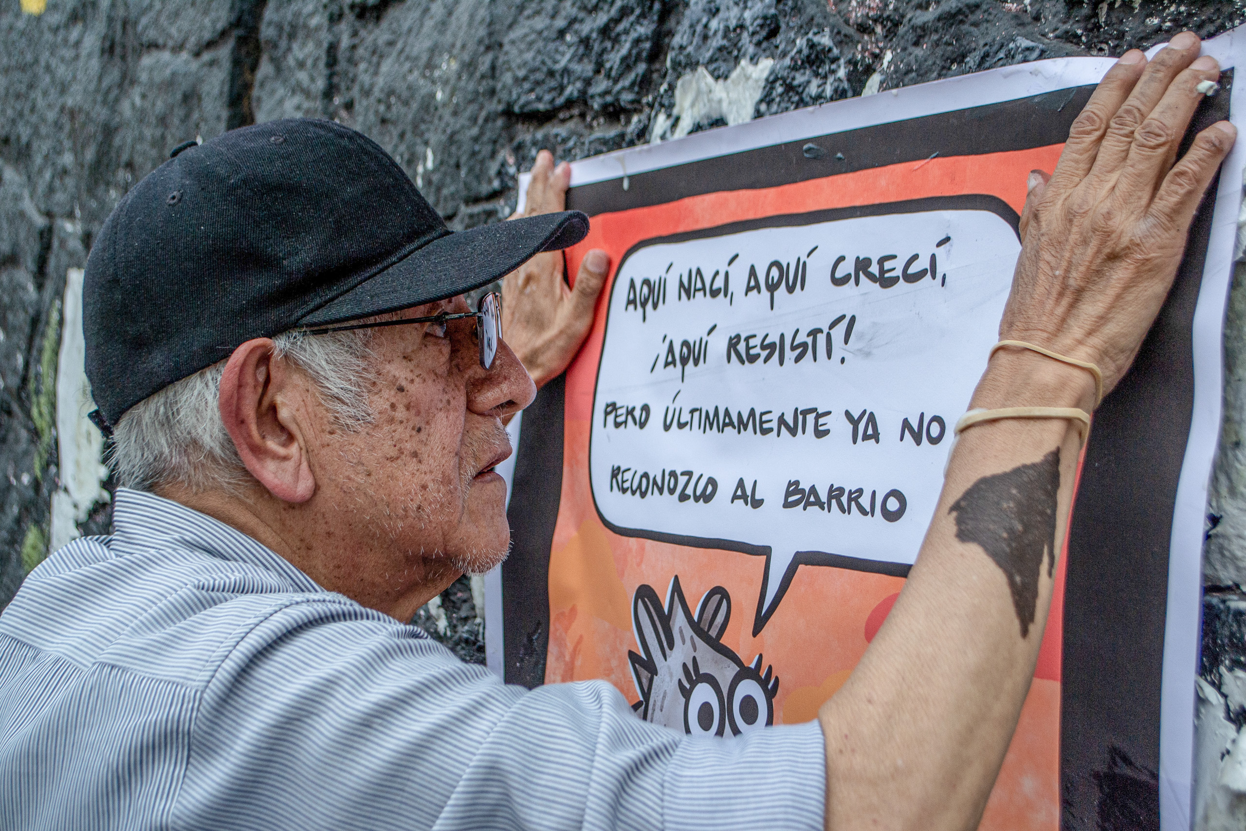 Morador de Santa Úrsula Coapa cola cartaz em muro de pedra