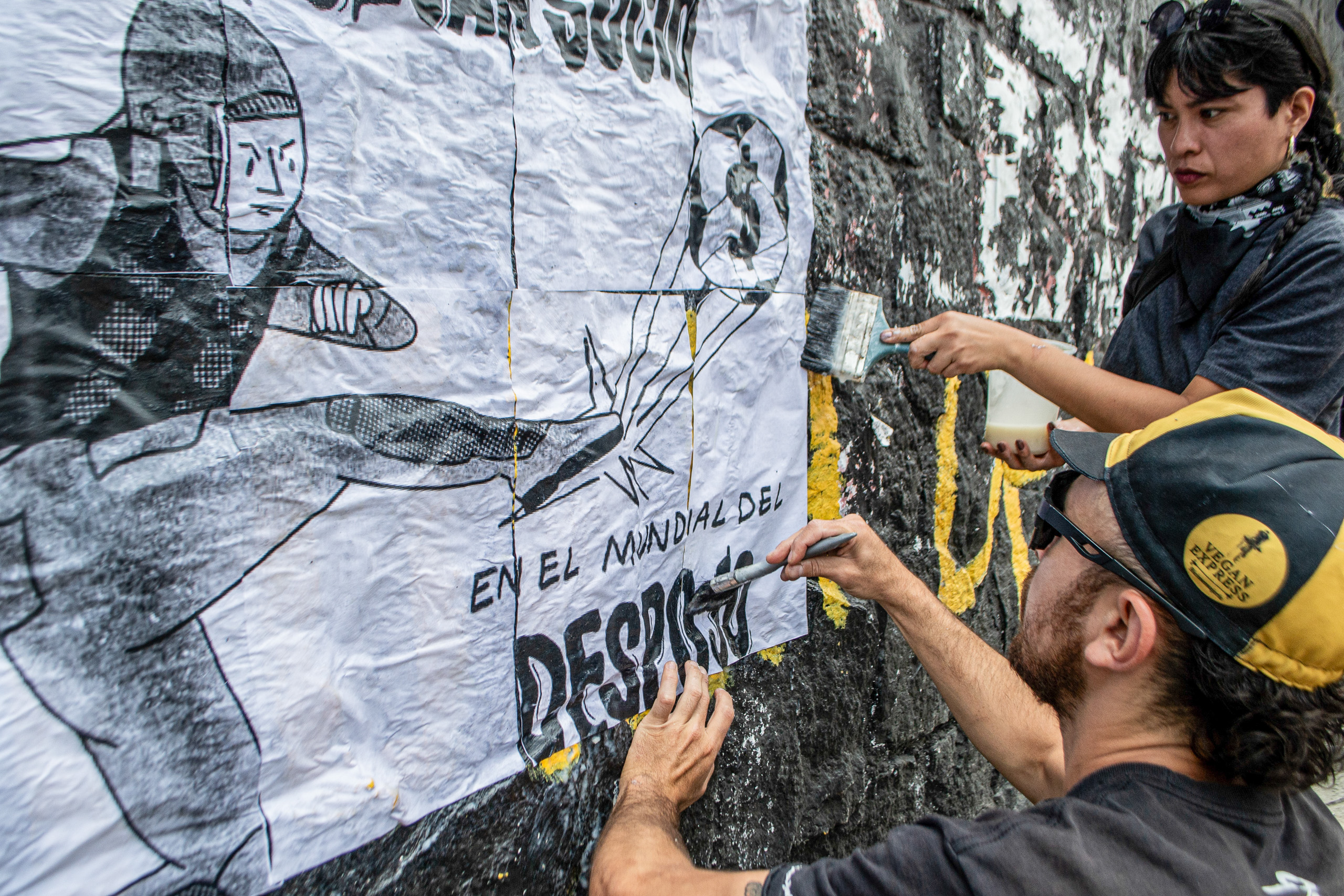 two people putting poster on wall