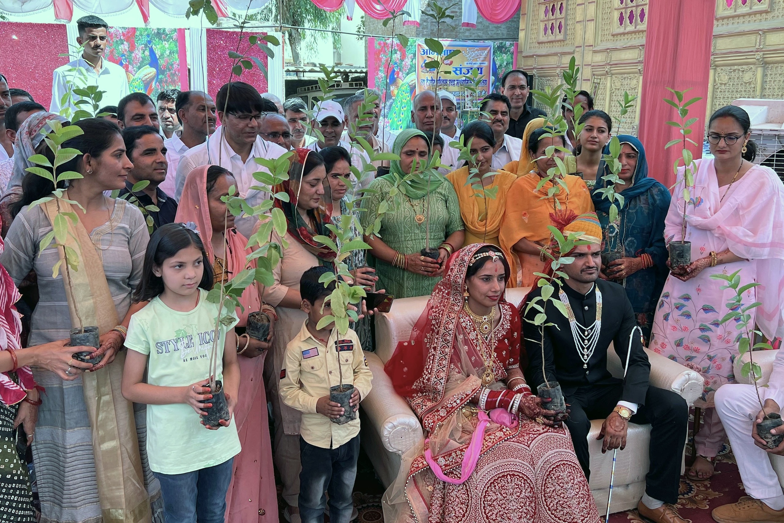 <p>A wedding in Rajasthan’s Lunkaransar village with the bride, groom and their family members holding tree saplings, which will be planted as part of the ceremony and adopted as kin (Image: Avani Jyani)</p>