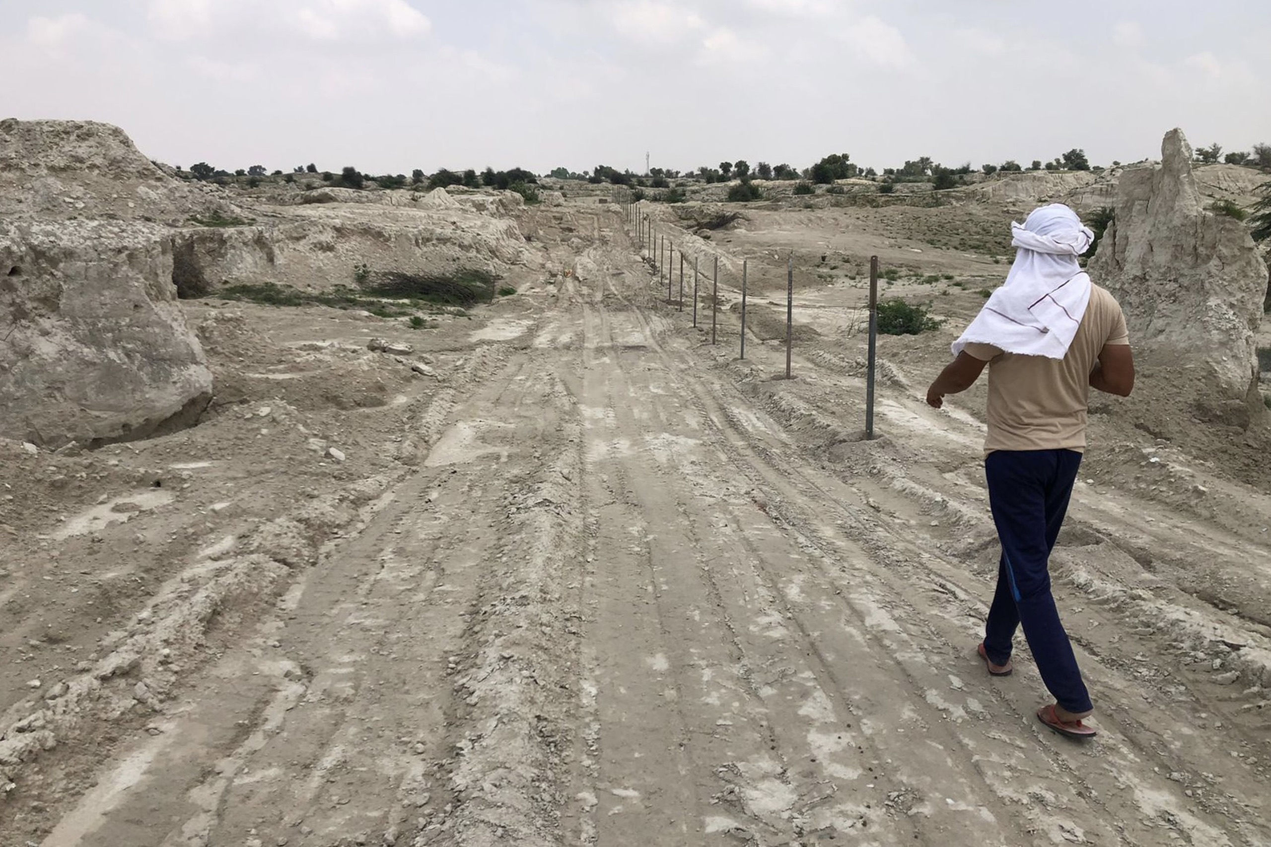 Man in white headscarf walks on a dirt path