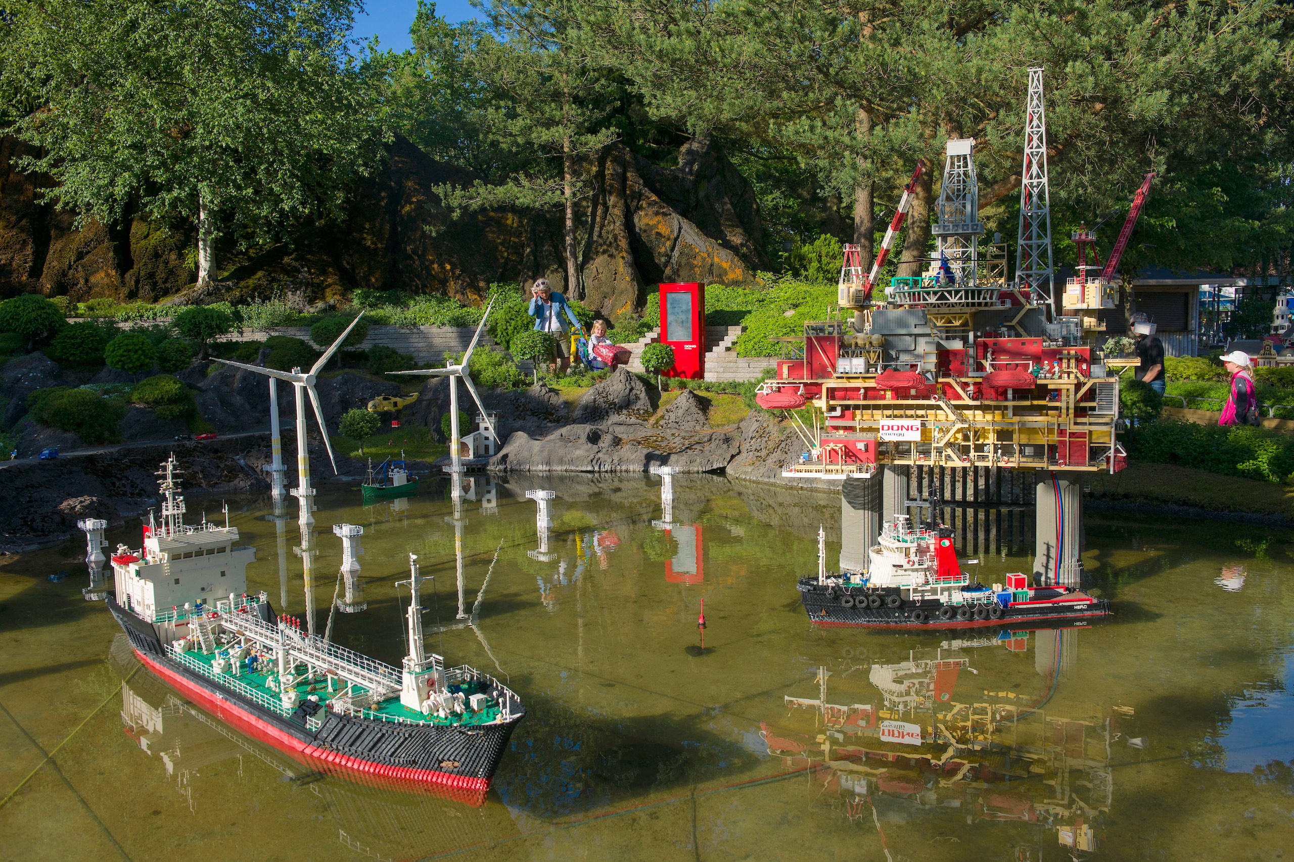 A Lego model ship and an oil drilling platform in a pond in an amusement park 