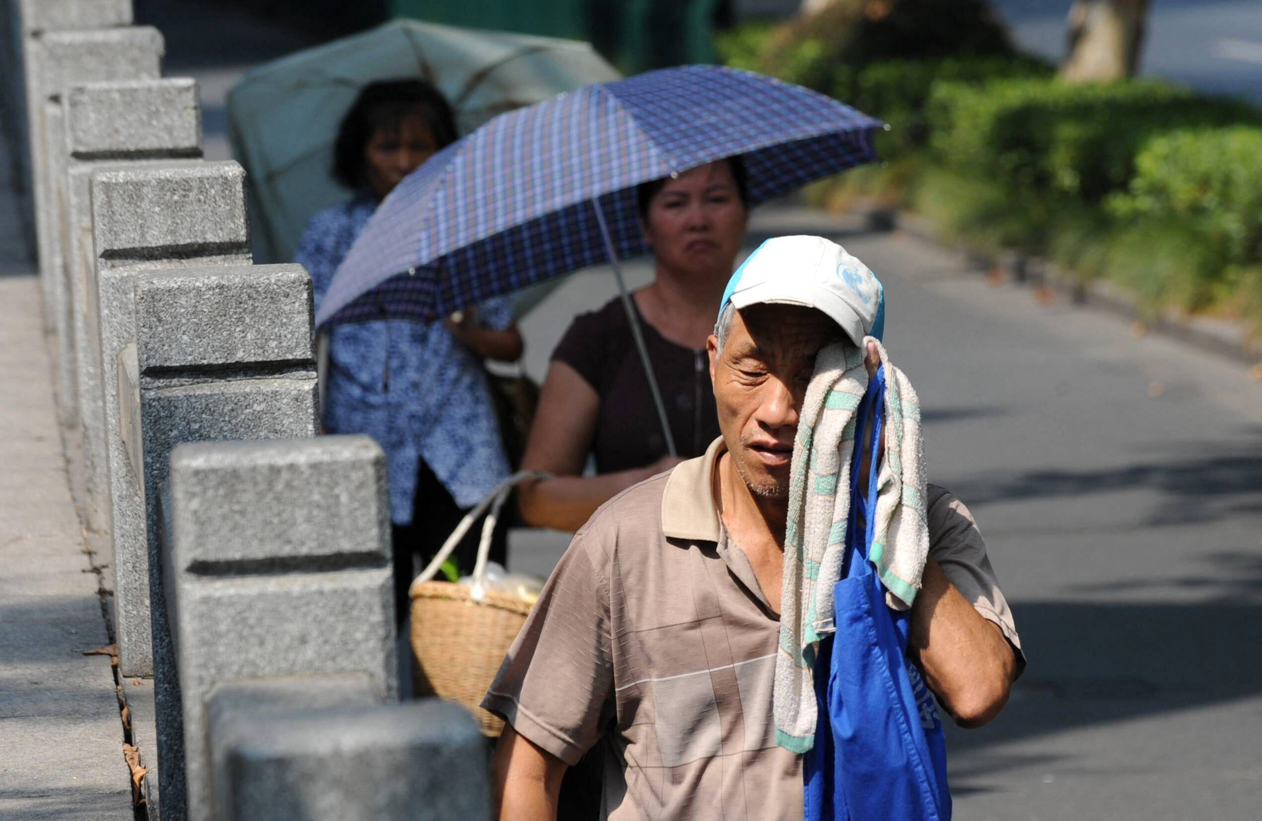 elderly man on street wipes sweat from face