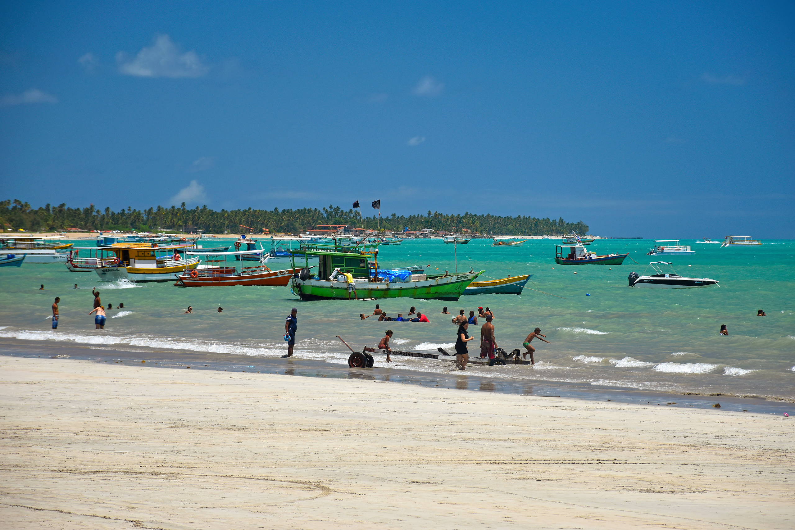 gente y barcos en una playa con mar turquesa