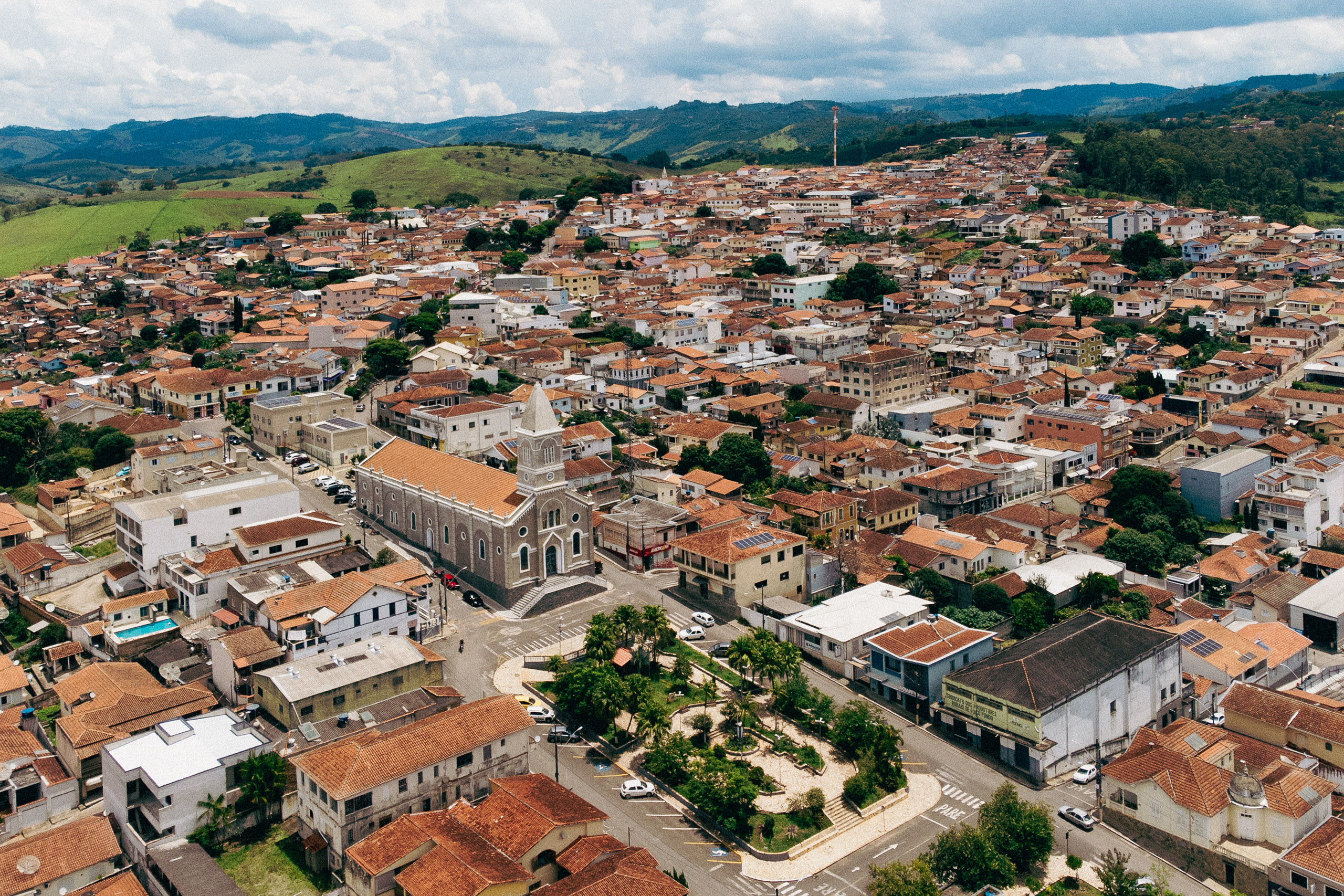 Aerial view of a small town with a central church, red-tiled roofs, and surrounding green hills
