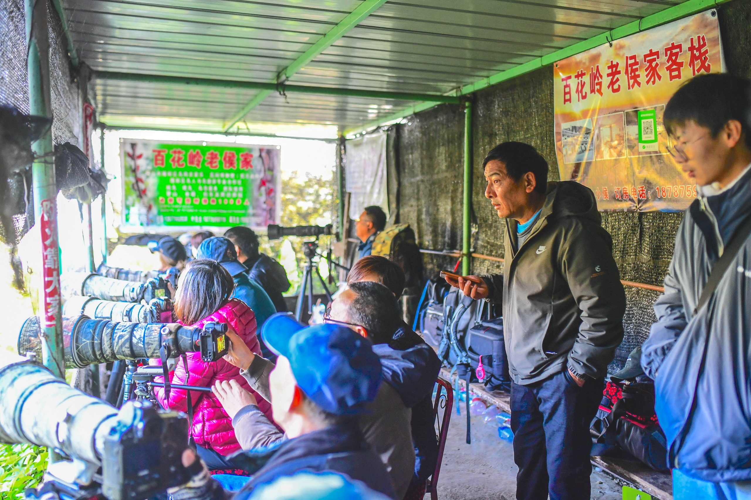 People with cameras and long lenses focus from a covered structure
