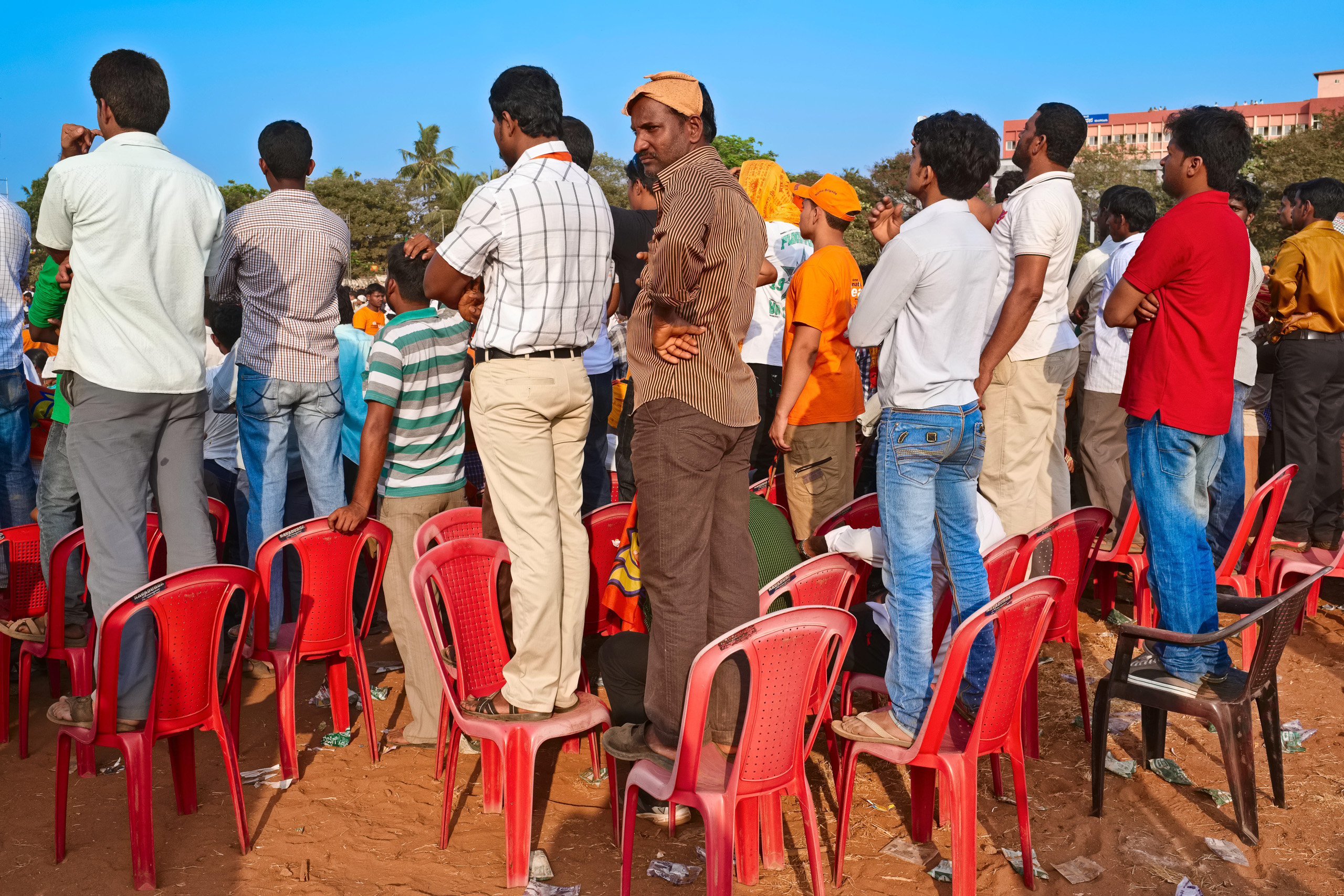 people in crowd standing on red plastic chairs