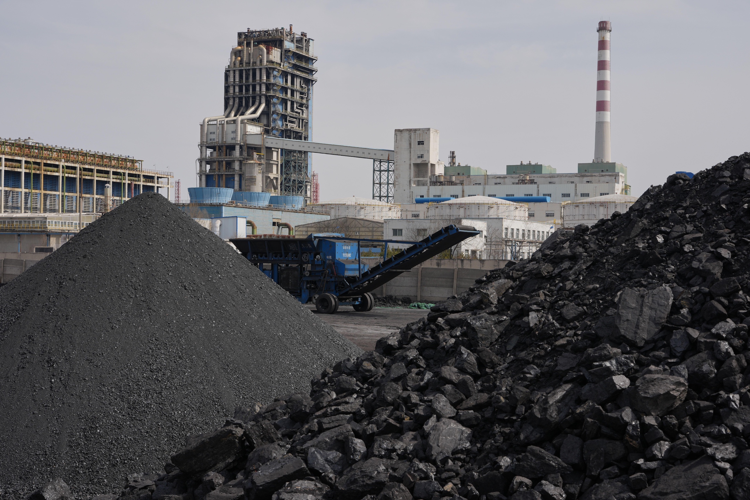 Piles of coal sit near a chemical plant
