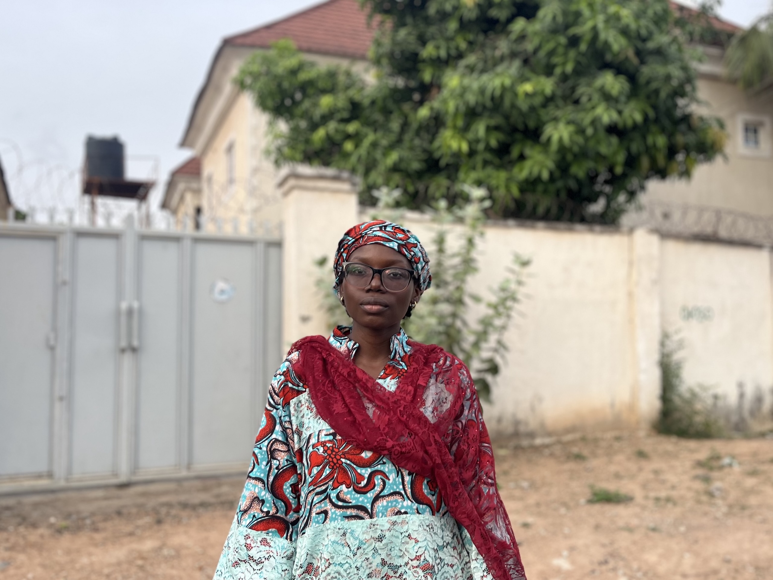 A woman in a vibrant dress stands in front of a house