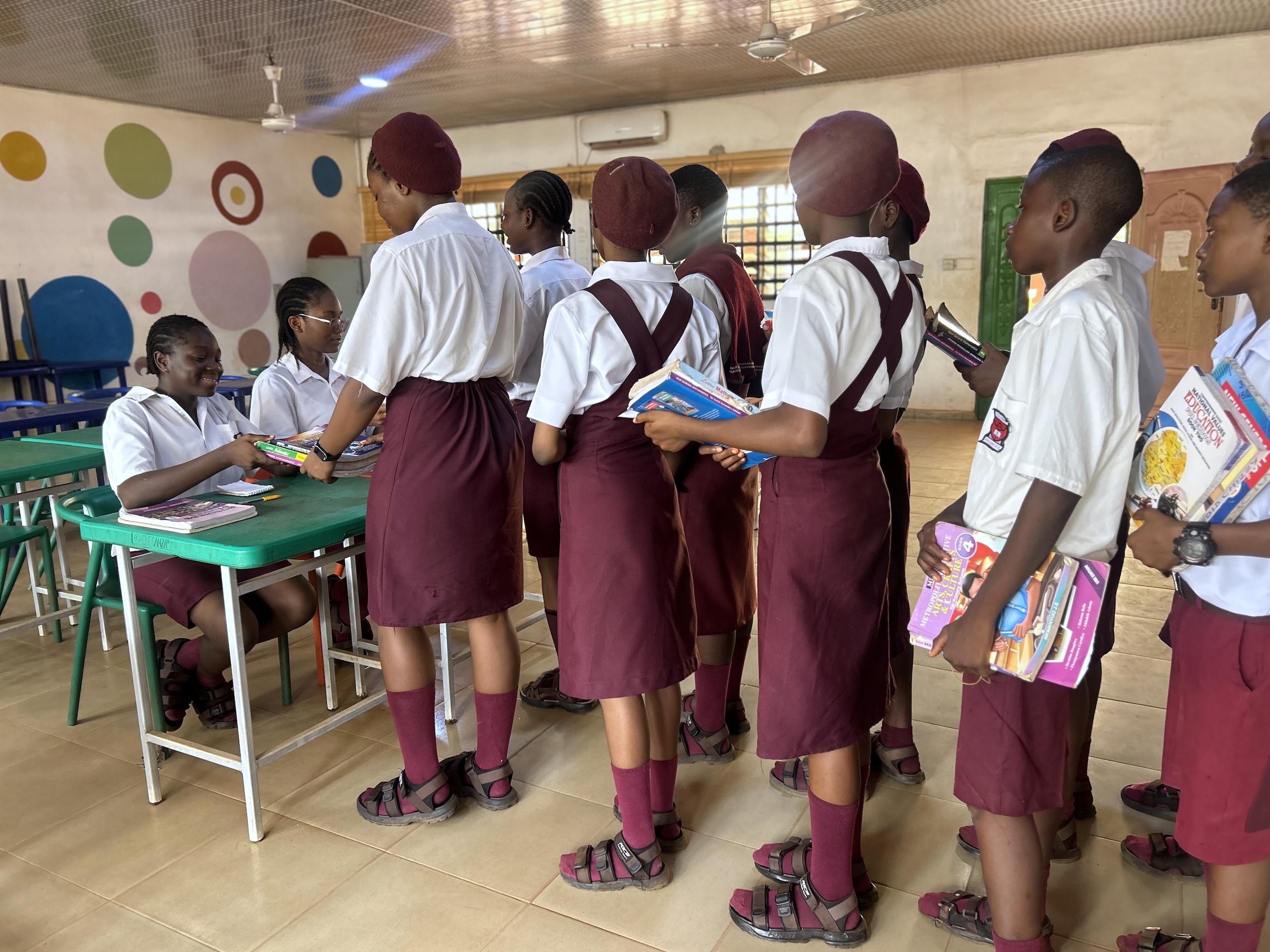 Students in uniforms in queue, donating books