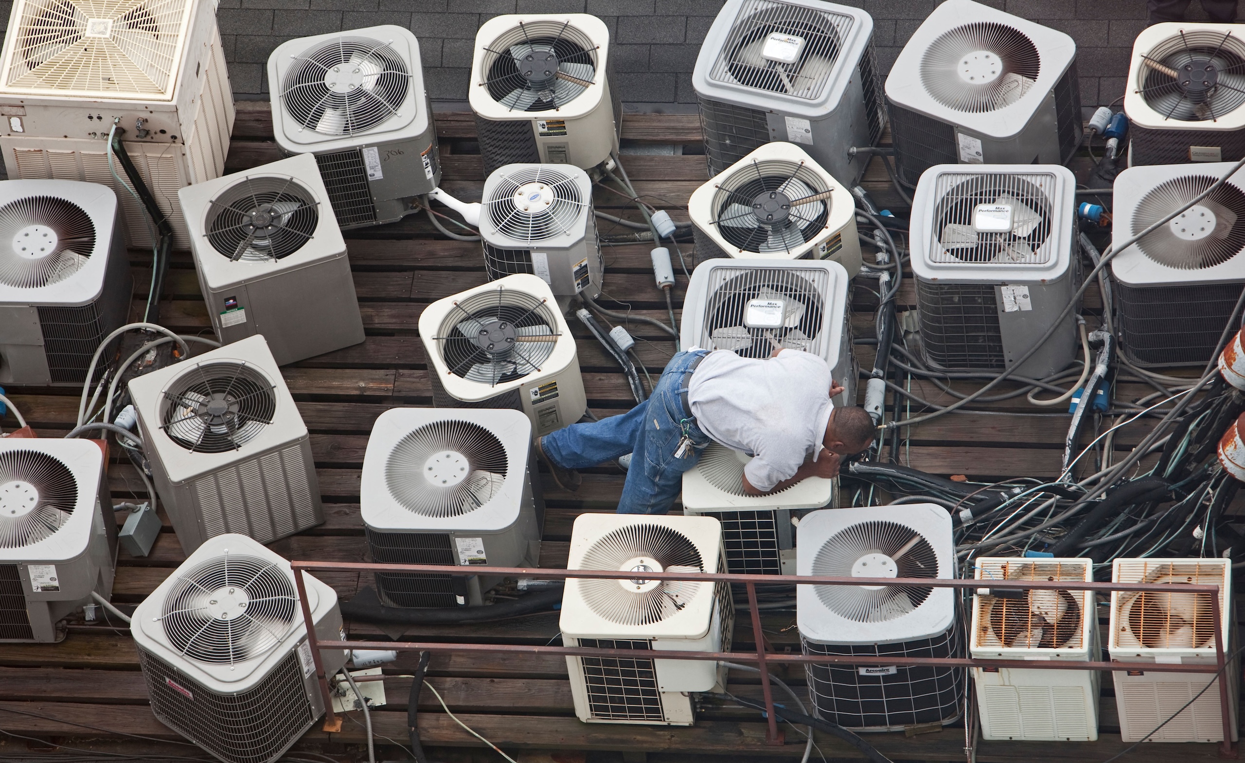 <p>A technician inspects AC equipment on the roof of a building in Louisiana, US (Image: Jim West / Alamy)</p>
