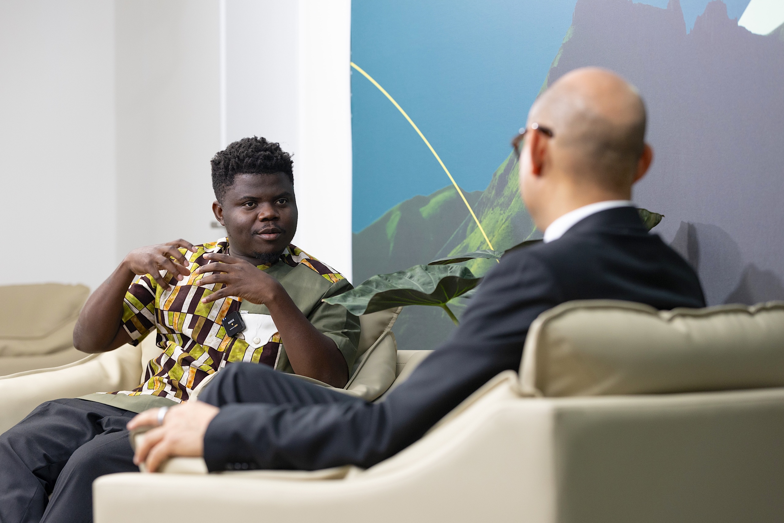 Two men sit on chairs having a conversation