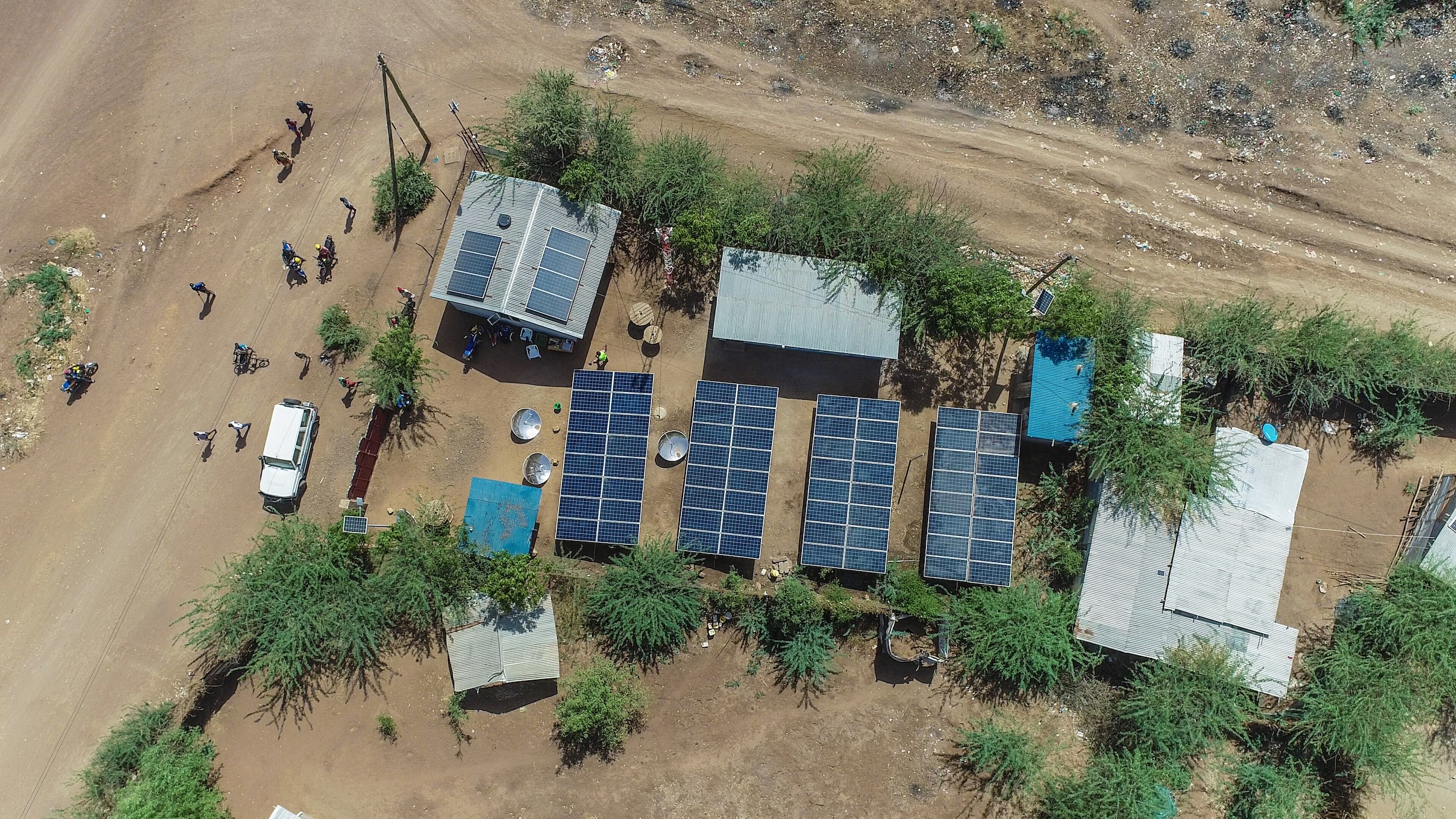 Aerial view of multiple buildings with solar panels on roofs in a rural area