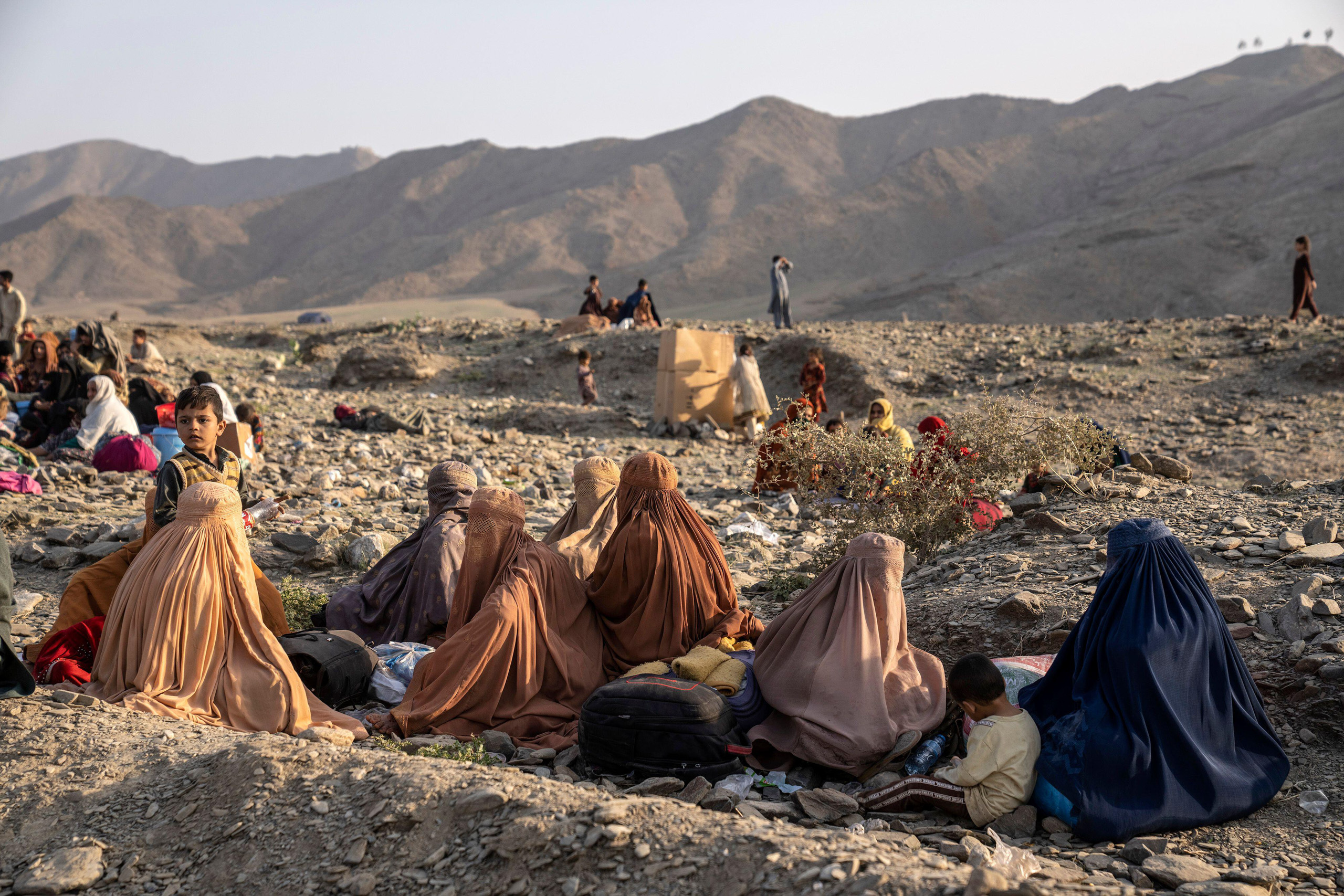 women and children sitting on dusty ground
