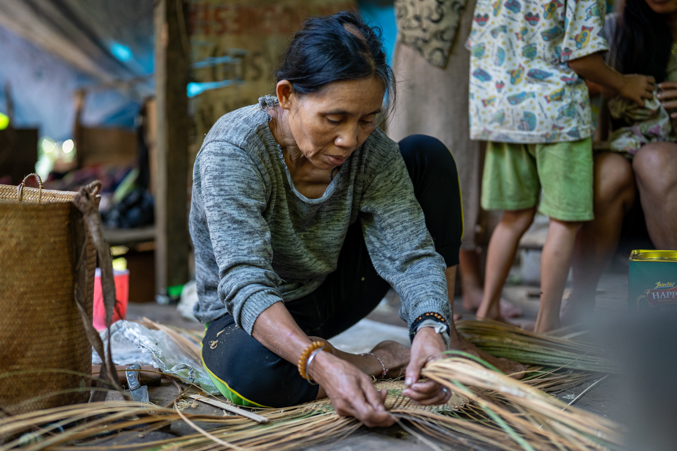 A woman weaves a basket using rattan 