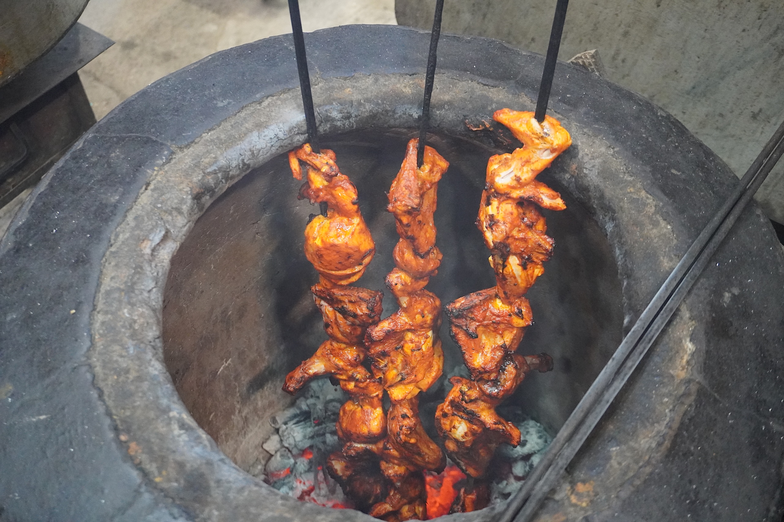 Chicken kebabs skewered and cooking in a tandoor