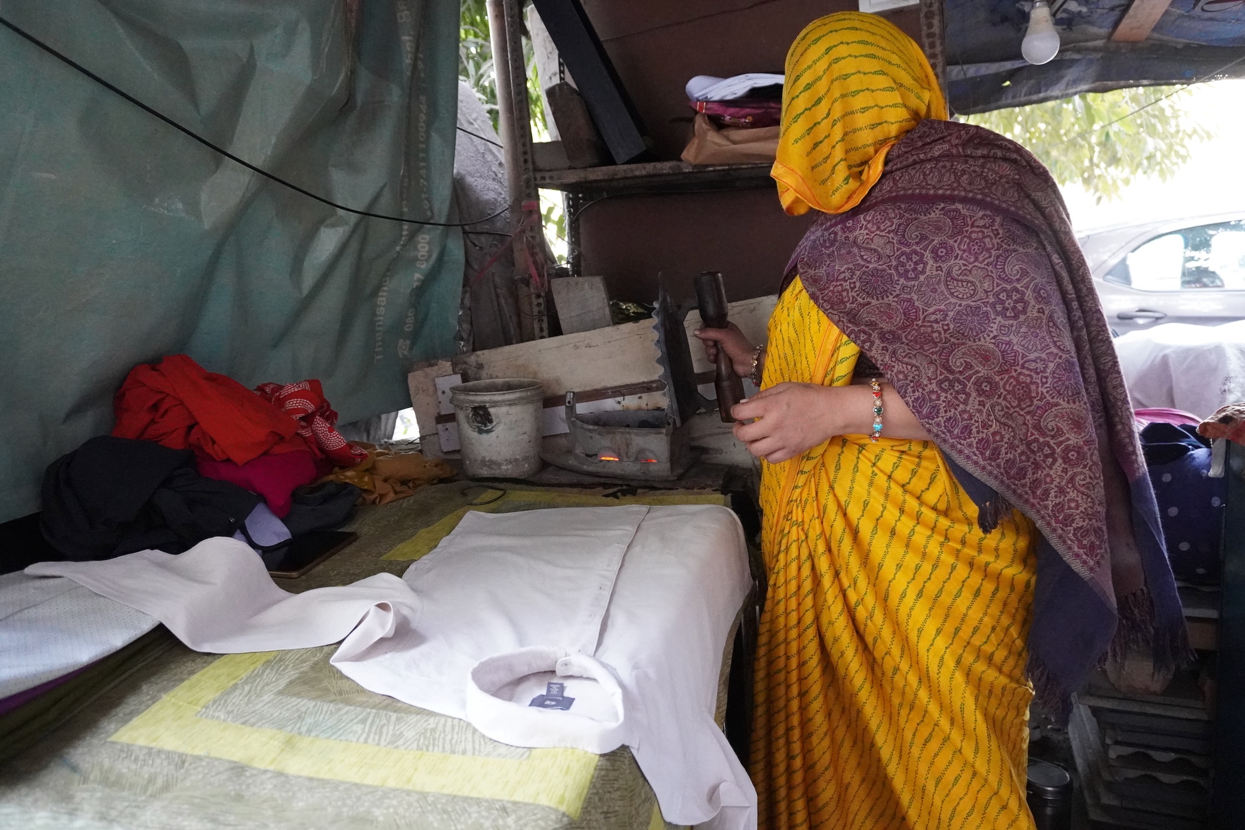 a woman irons clothes at a shack