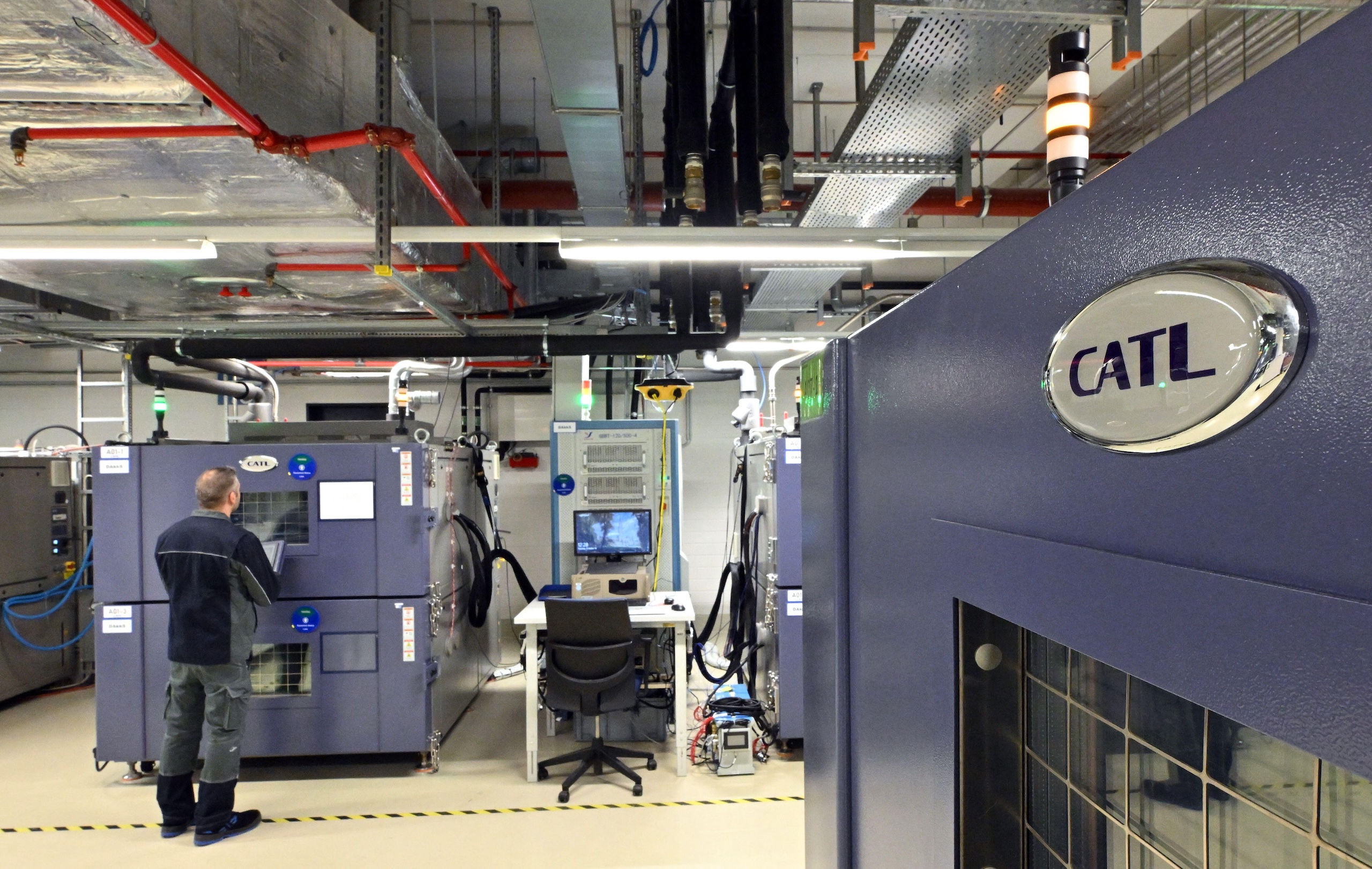 A man stands in front of machine in a room filled with a computer and various machines