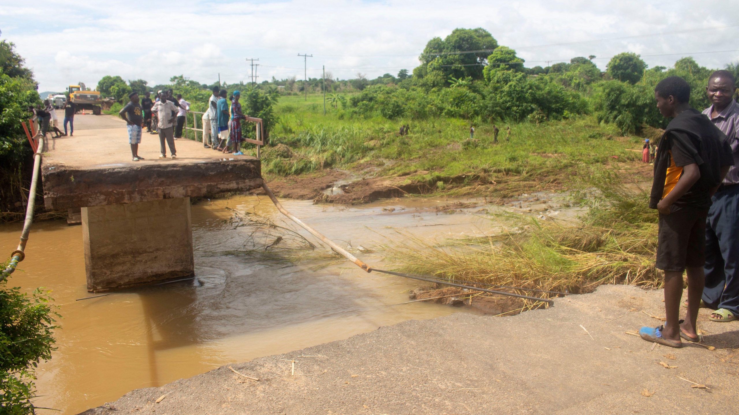 People stand on the edge of a damaged bridge