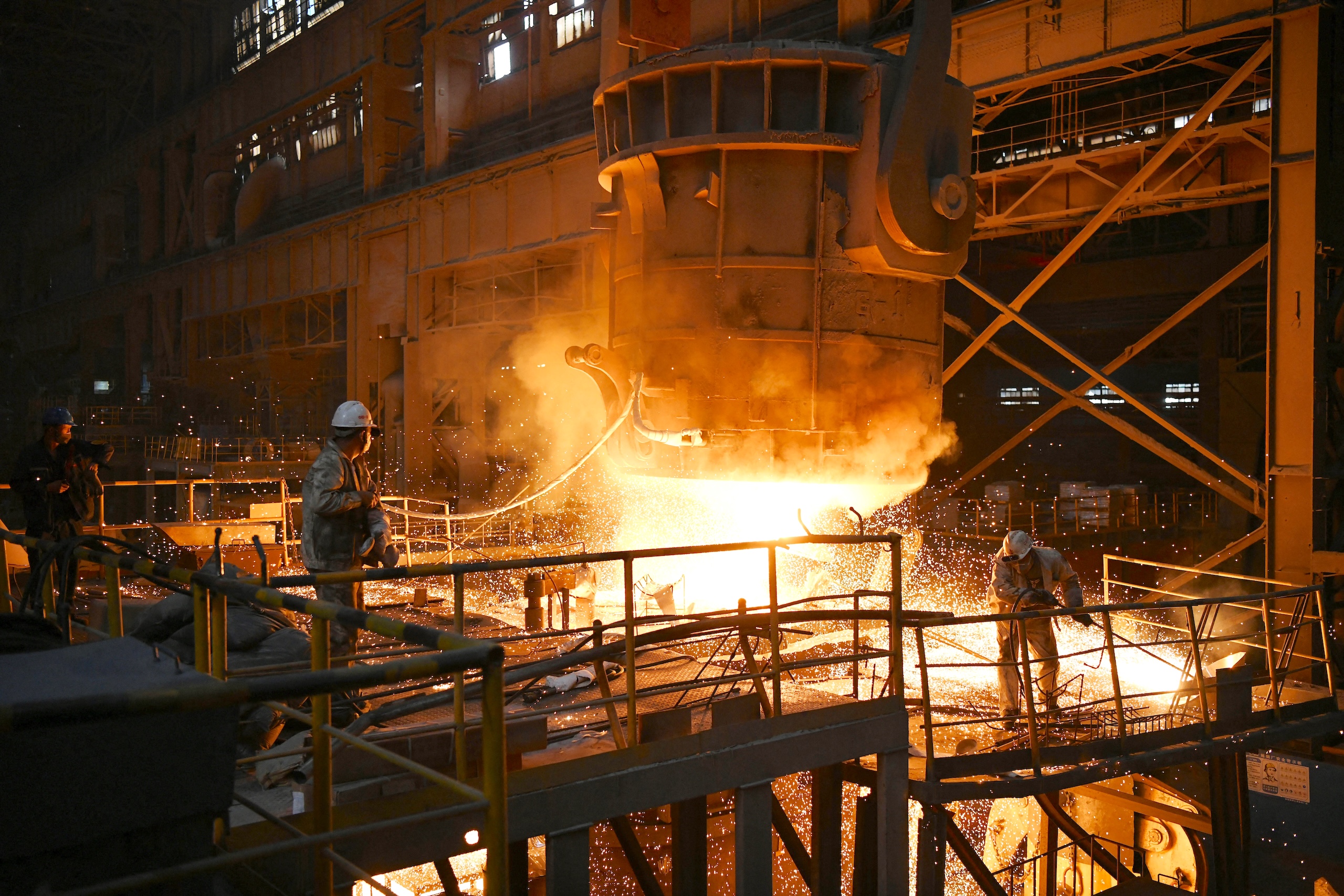 Workers pour molten steel into molds at a steel plant