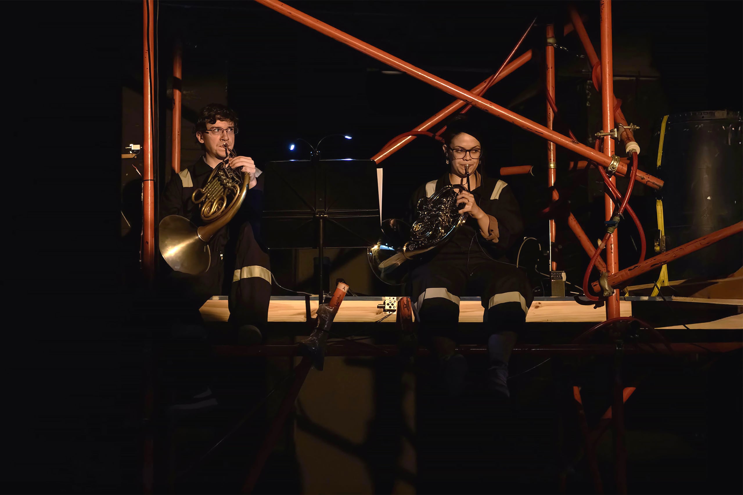 Dos músicos vestidos con mamelucos de trabajo tocando el corno