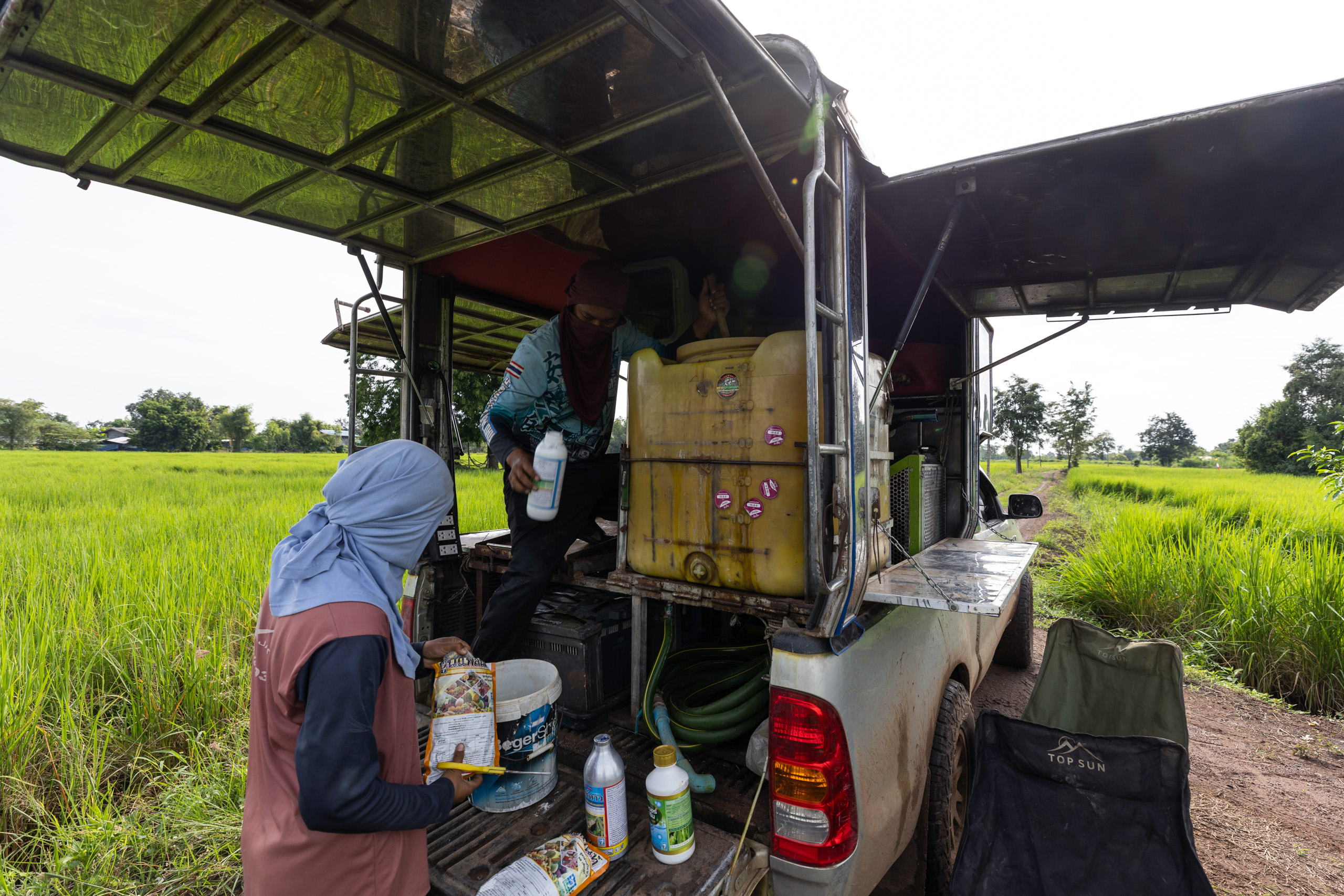 An agricultural drone pilot and his assistant mix a concoction of fertilisers and pesticides