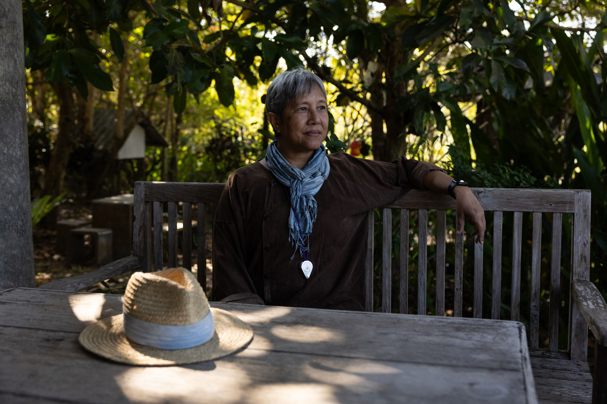 A woman seated at a table, with a basket of fresh oranges beside her