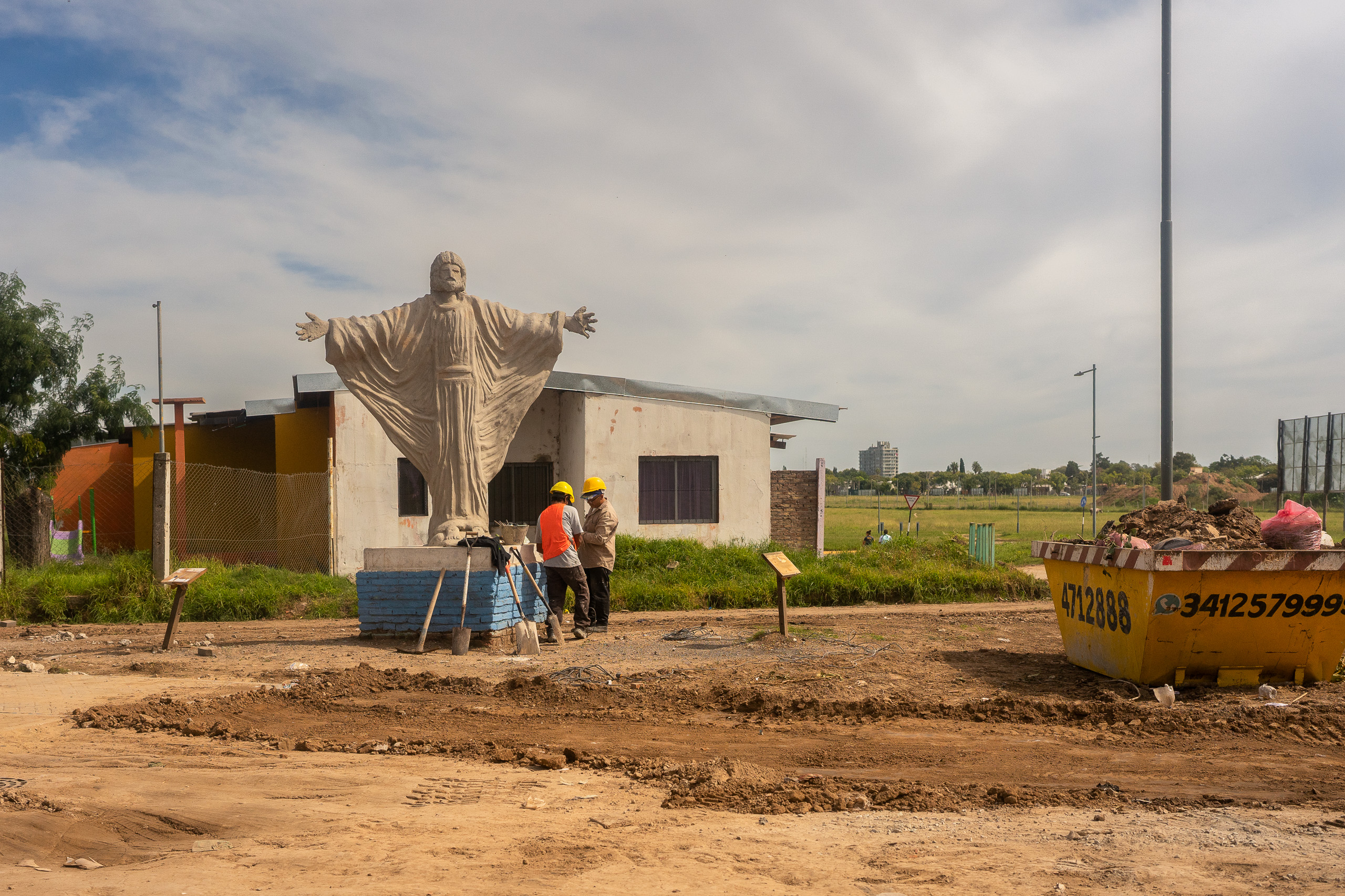 Estatua de Jesús en medio de un obra en construcción y obreros