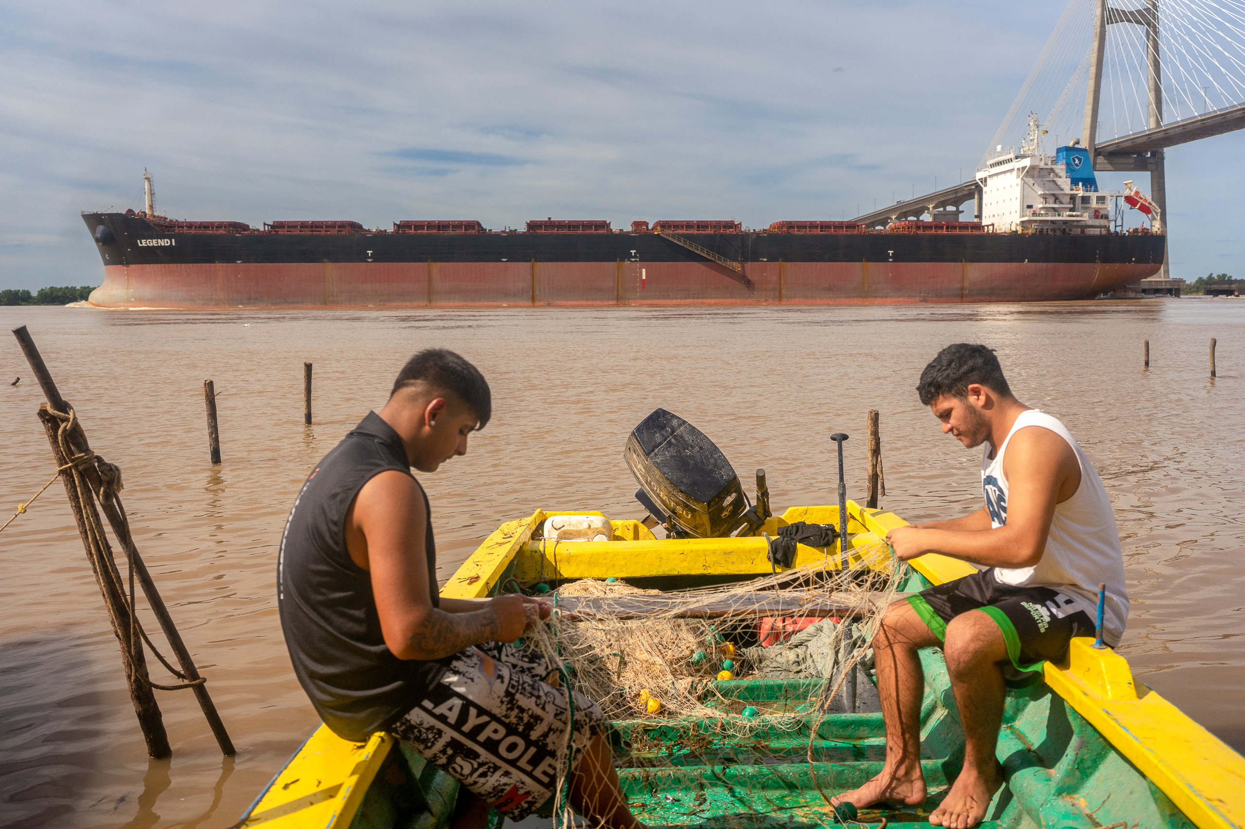 Dois pescadores jovens desembaraçam redes de pesca
