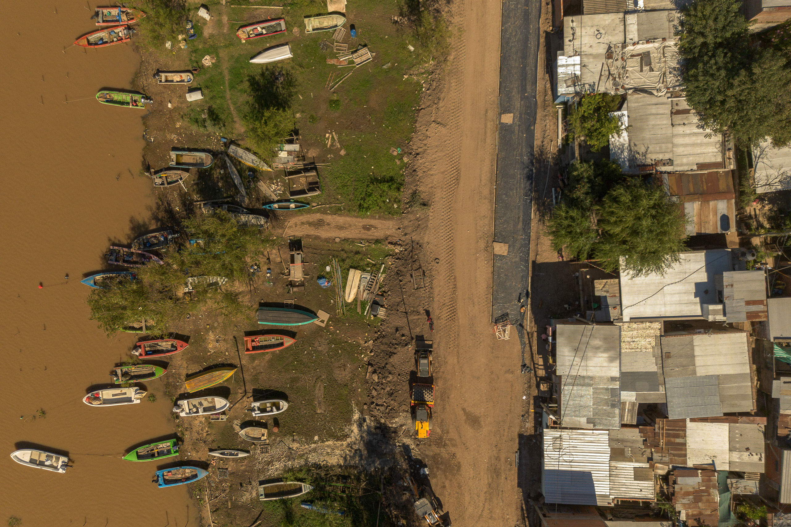 Vista aérea de barcos amarrados a lo largo de la orilla de un río, con edificios al fondo