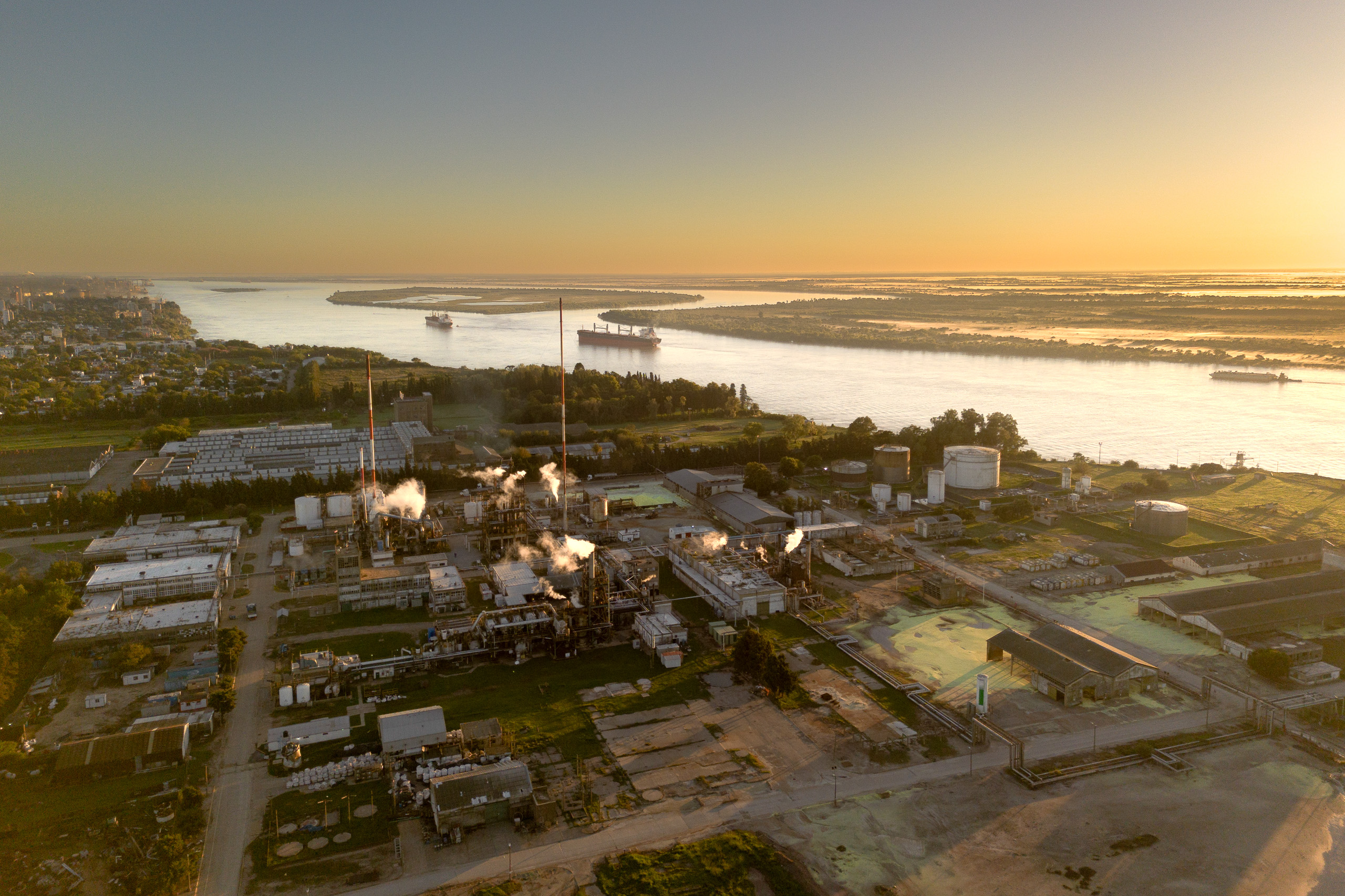 Vista aérea de un complejo industrial junto a un río al atardecer