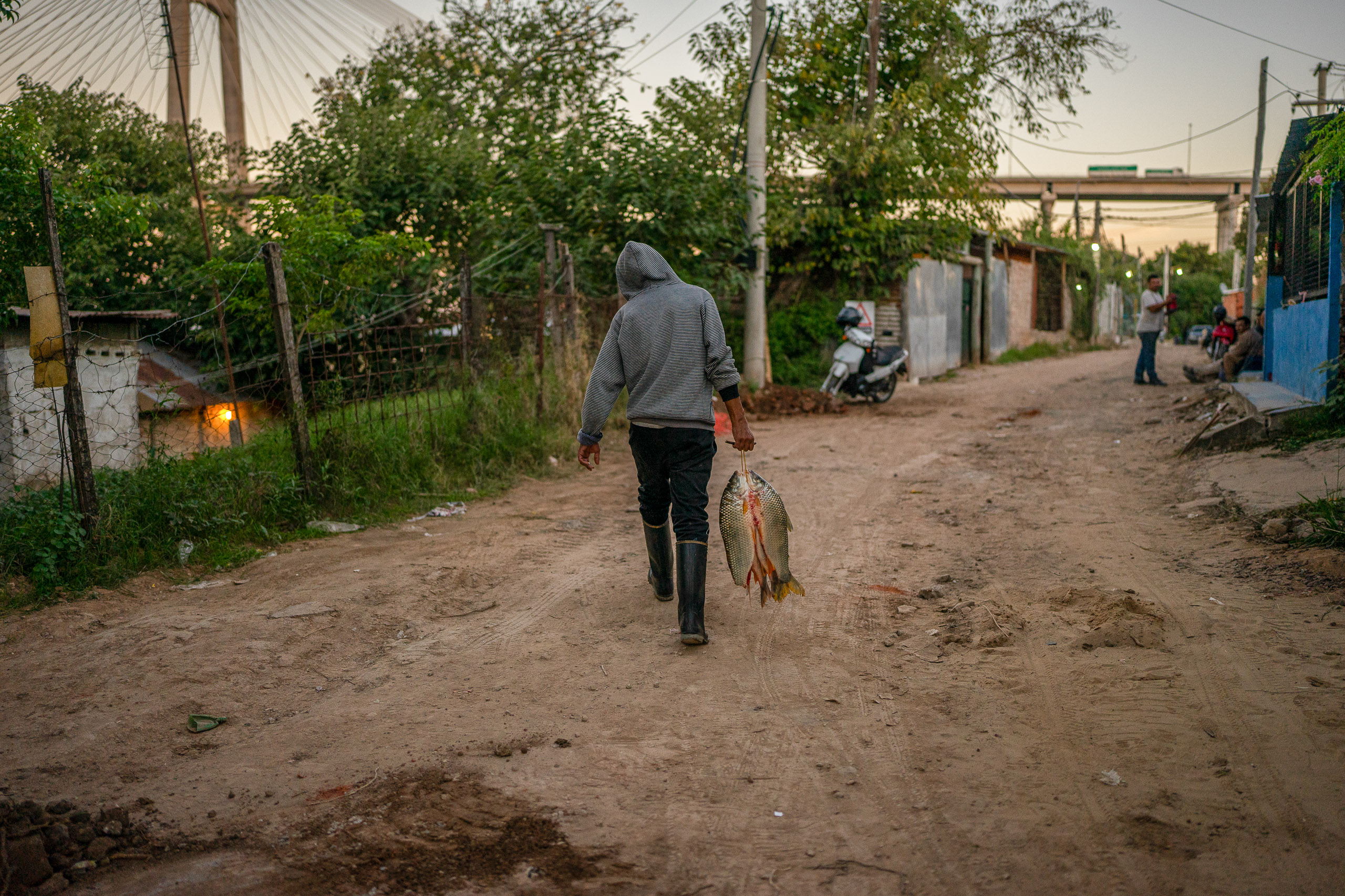 Un hombre que camina por un camino de tierra con un pez grande