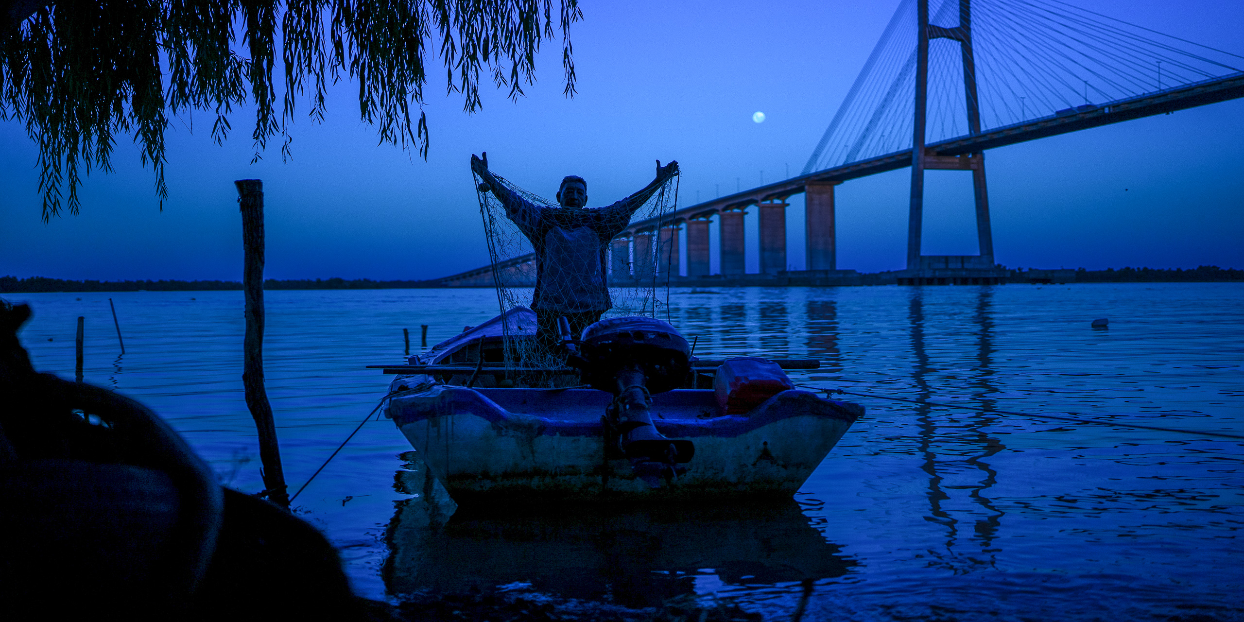 <p>Un miembro de una de las pocas comunidades pesqueras artesanales urbanas de Argentina arregla su red tras una salida al río Paraná (Imagen: Sebastián López Brach / Dialogue Earth)</p>