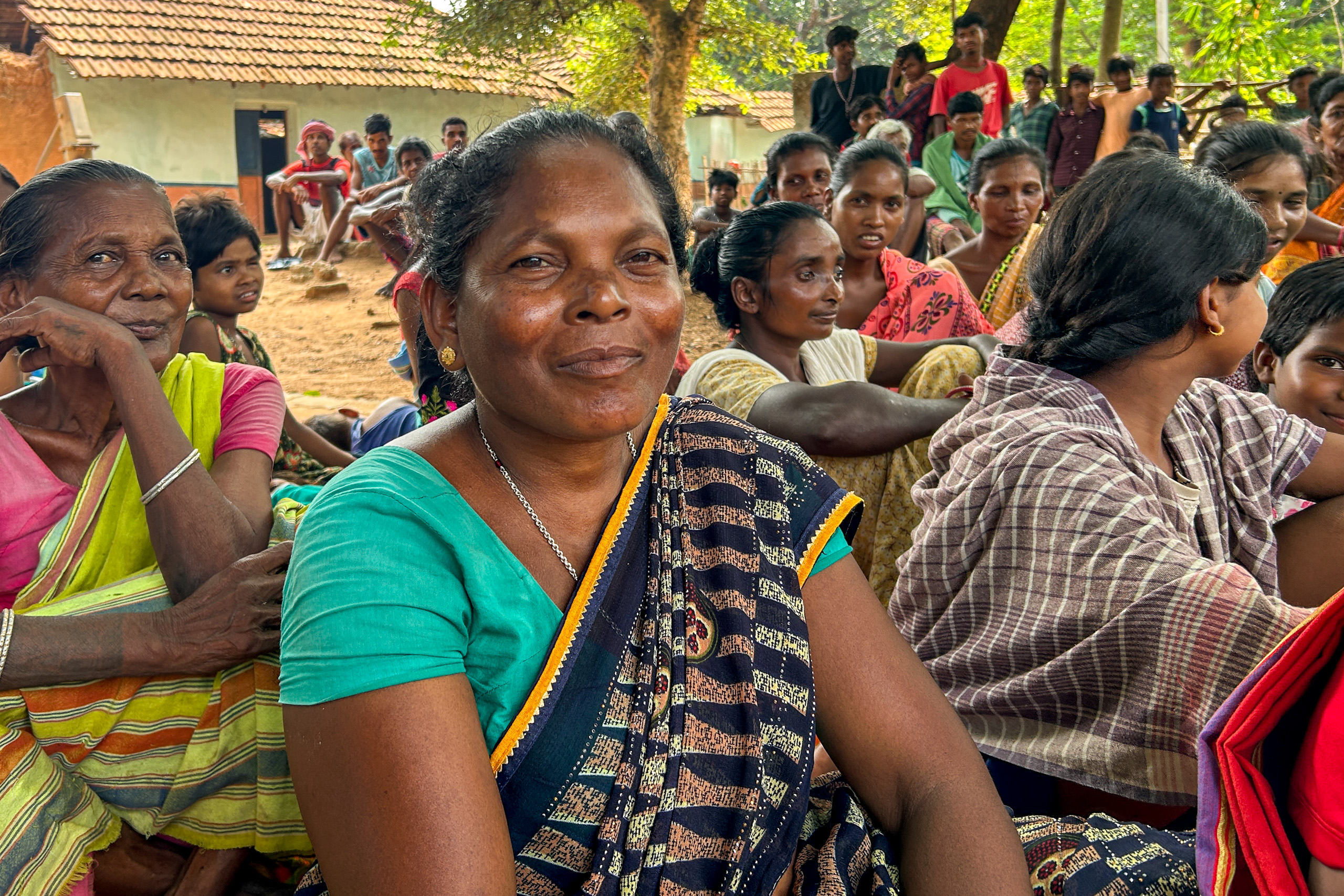 Women in traditional attire sitting on the ground gather for a meeting
