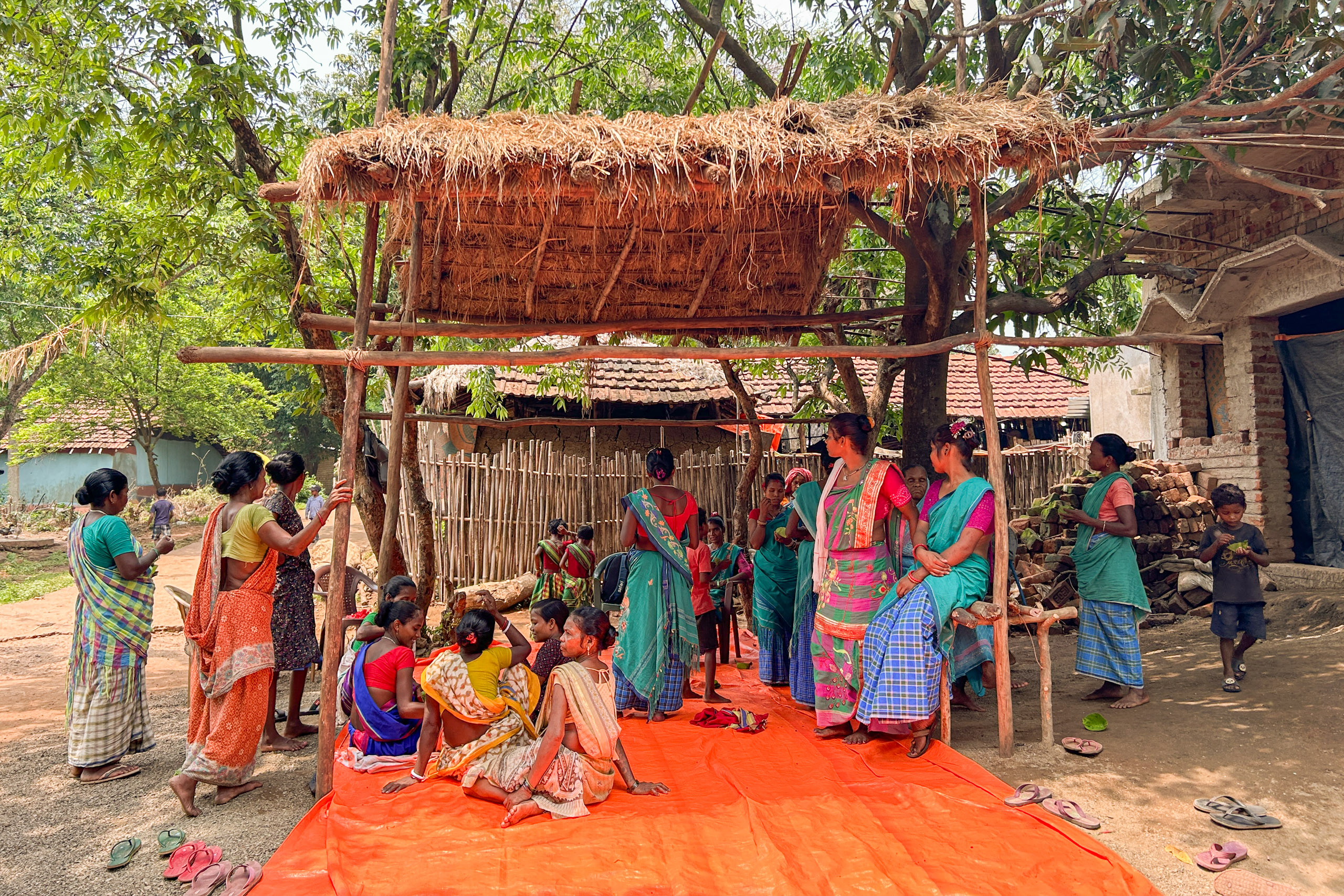 Women in green and blue traditional saris  gather around the shelter 
