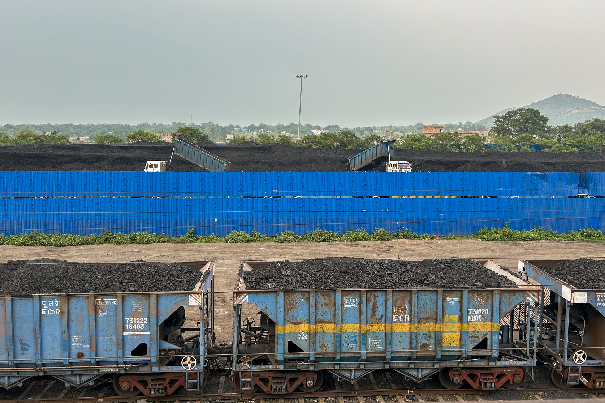 Coal-loaded wagons beside a storage yard near a station