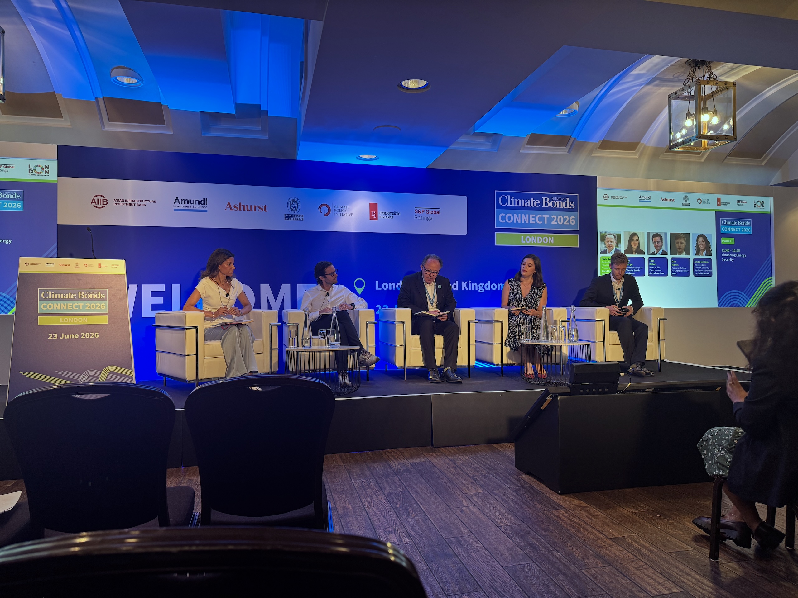  A panel of five individuals seated on stage, engaged in discussion at a conference