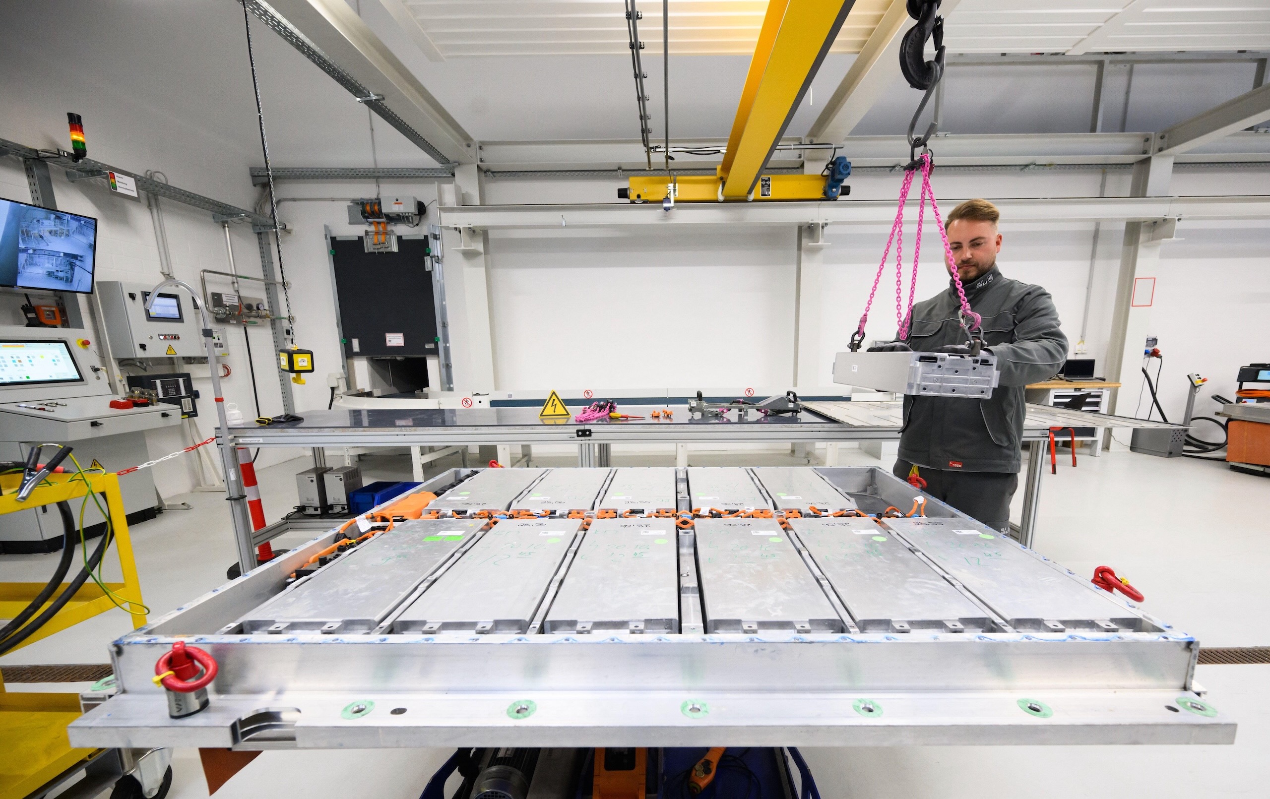 A worker removes a battery module from an electric car battery pack in a workshop
