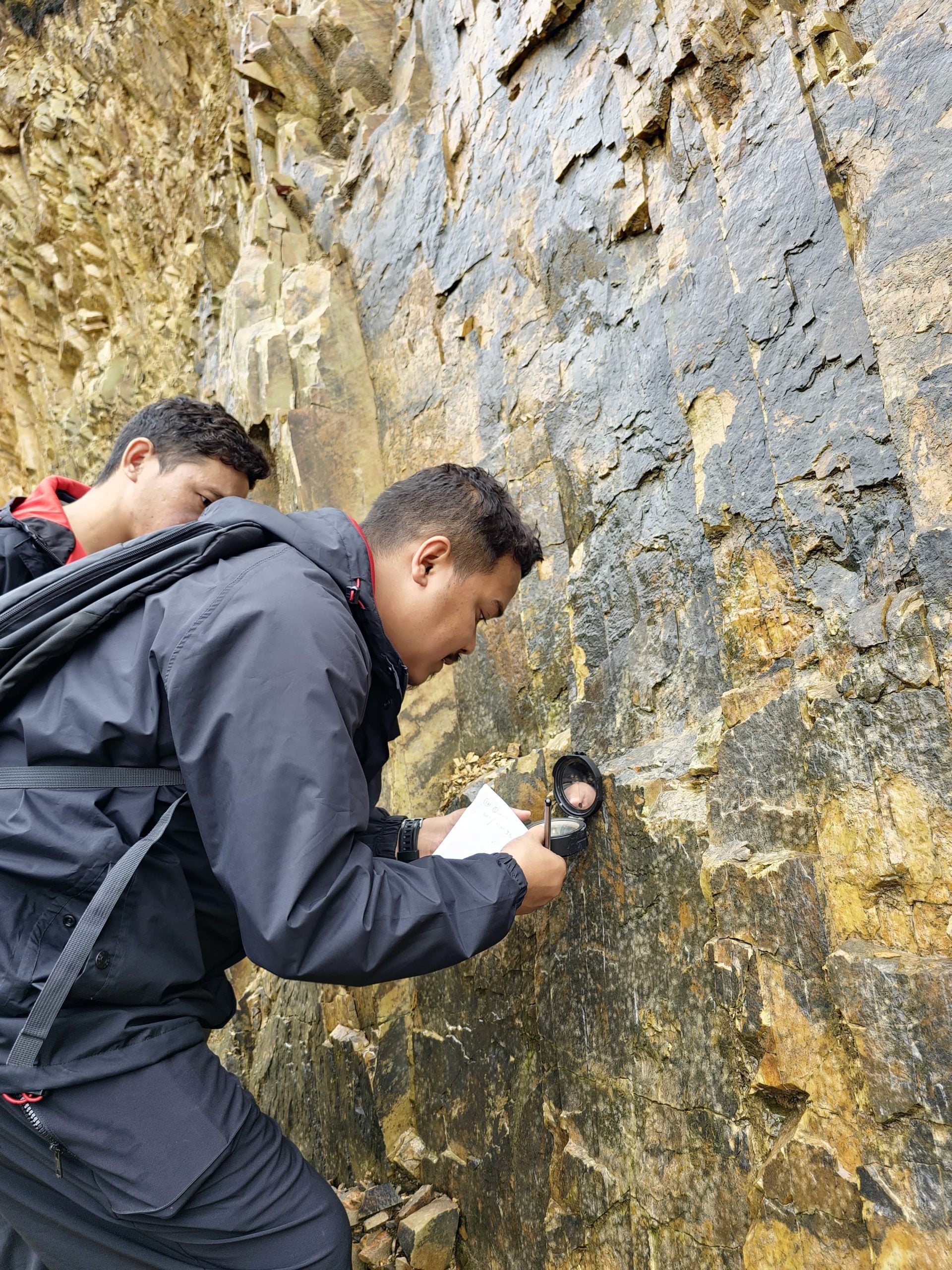 man collecting sample from rock face