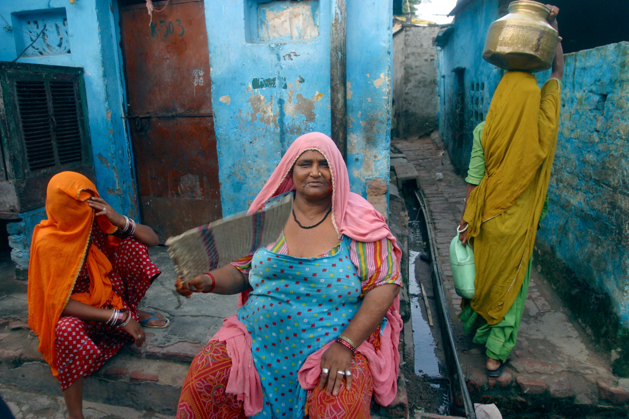 Three women site outside their house