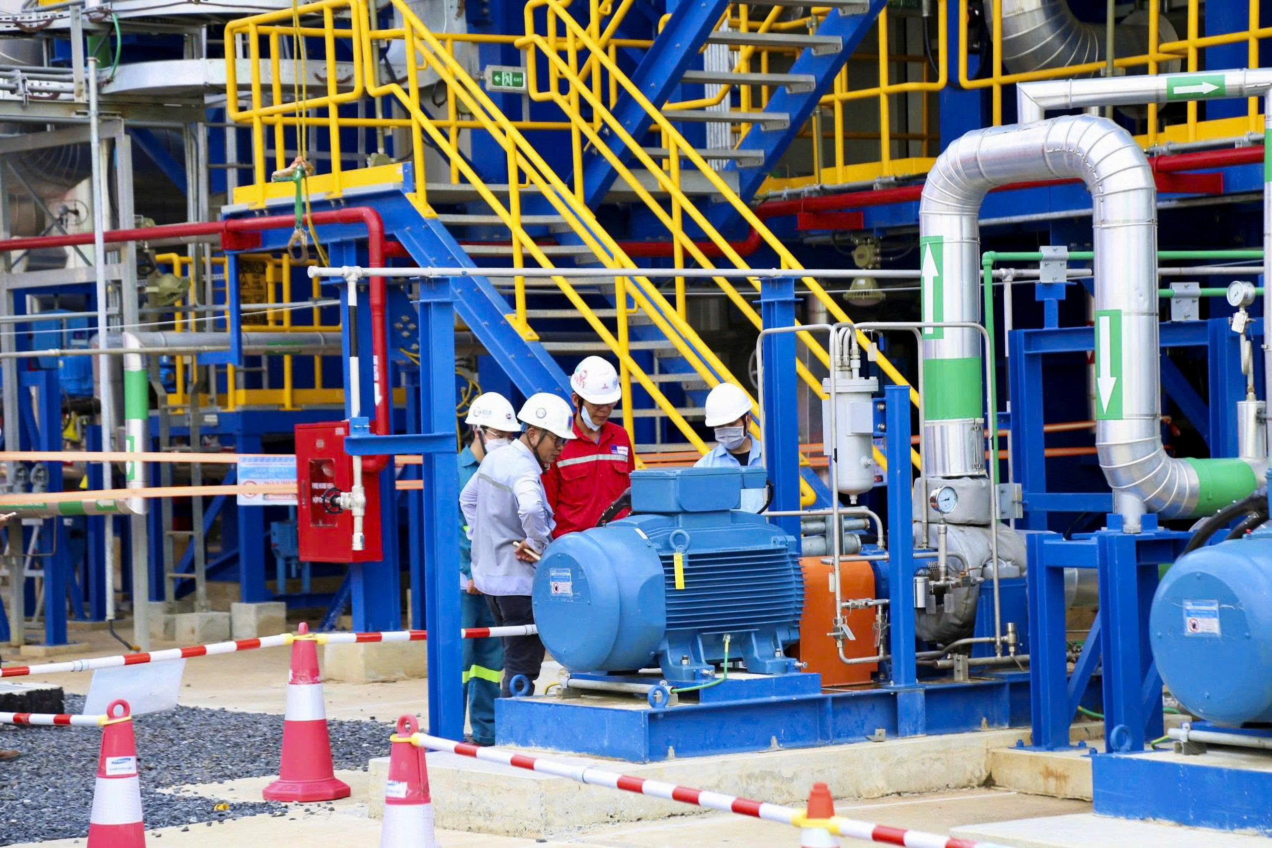 people wearing hard hats around machinery