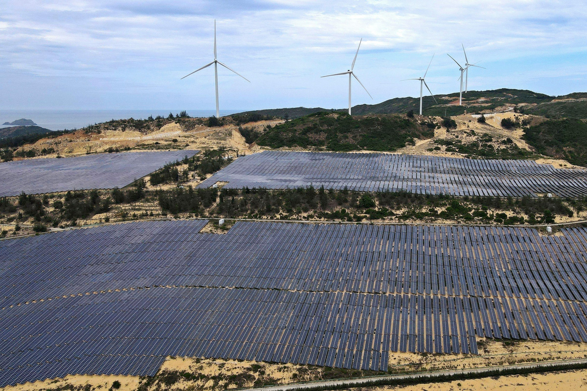 field of solar panels near wind turbines
